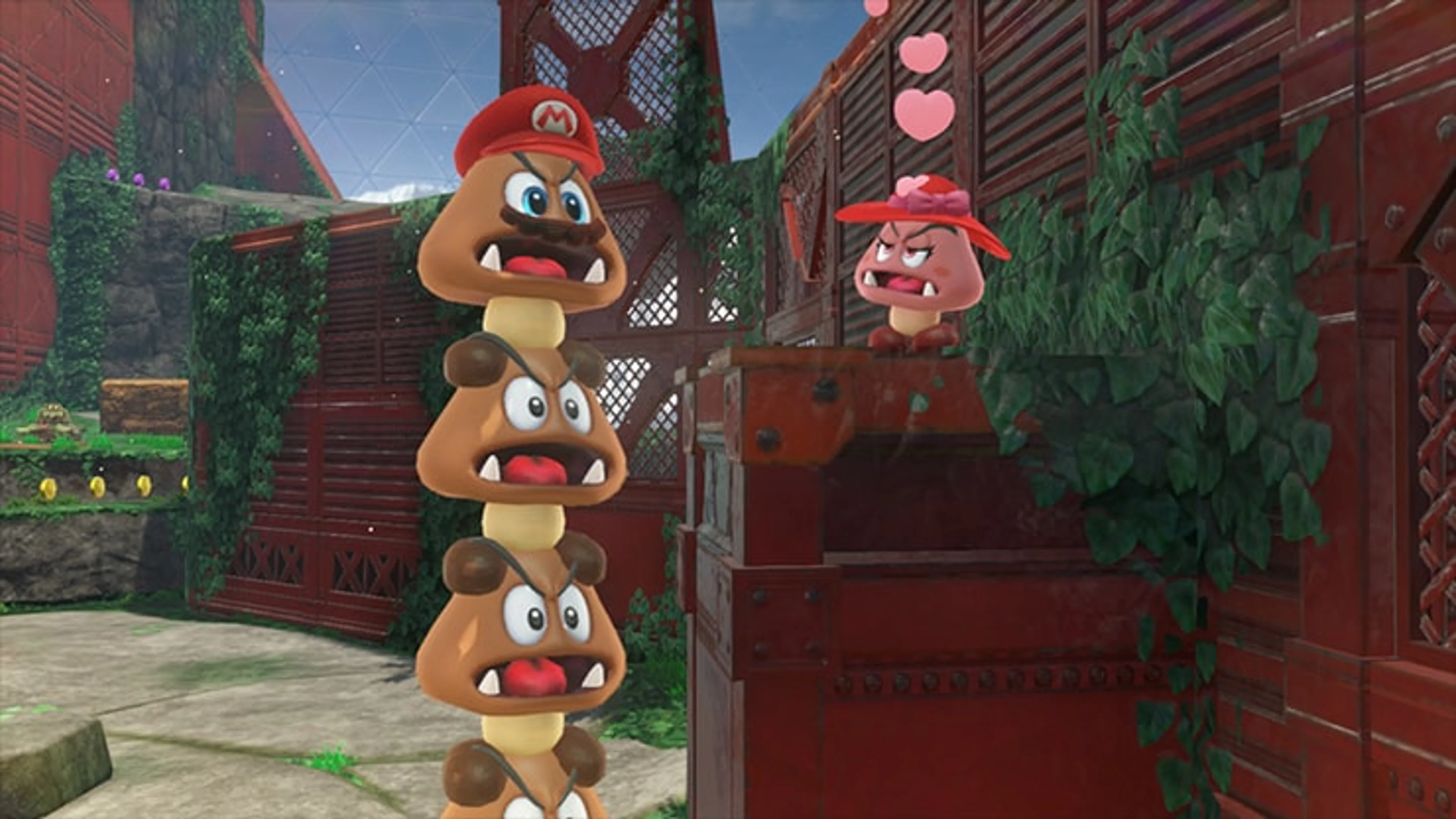 A stack of Goombas in a stone area wear Mario’s red cap with Cappy’s eyes.