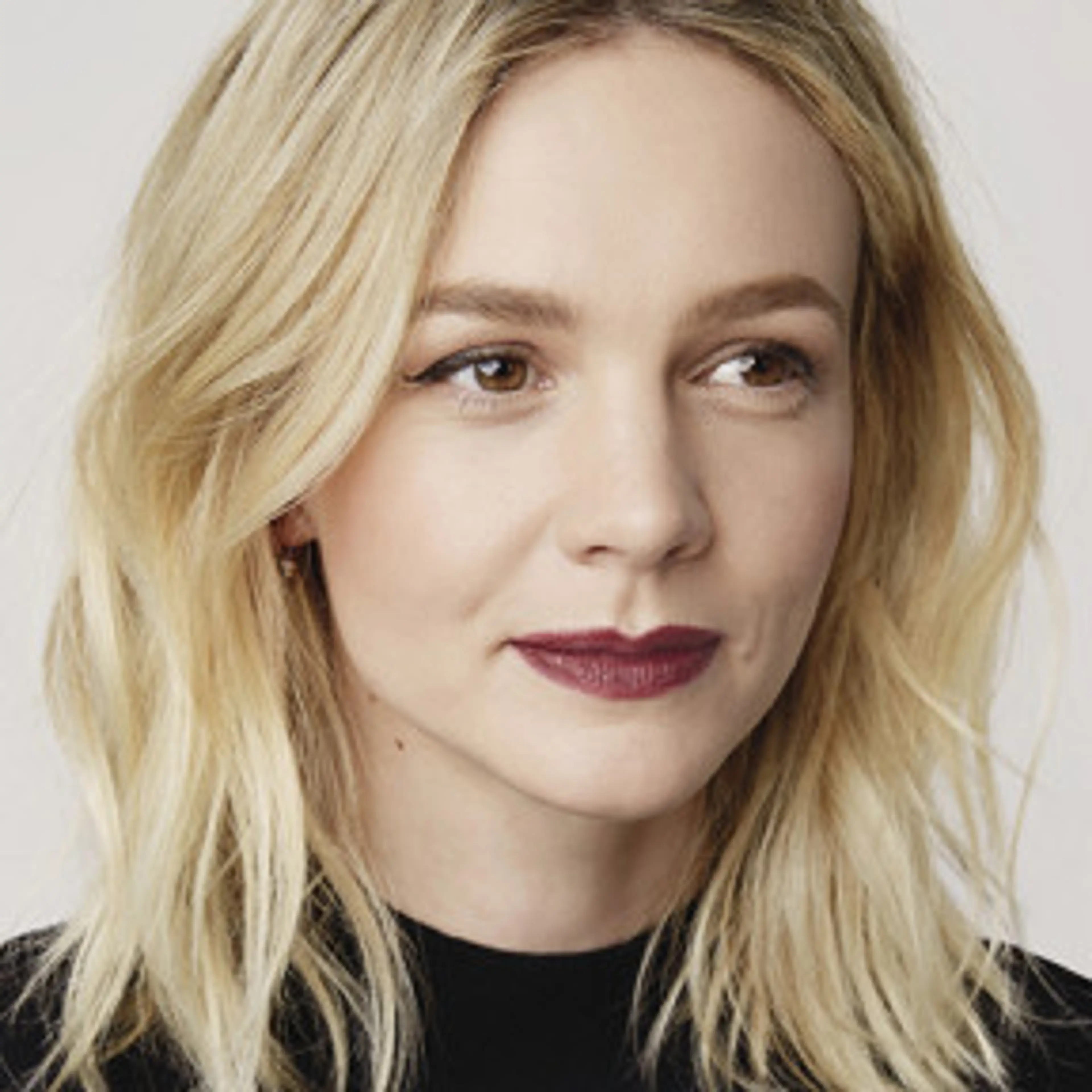 Portrait of Carey Mulligan with shoulder-length blonde hair and a black top.