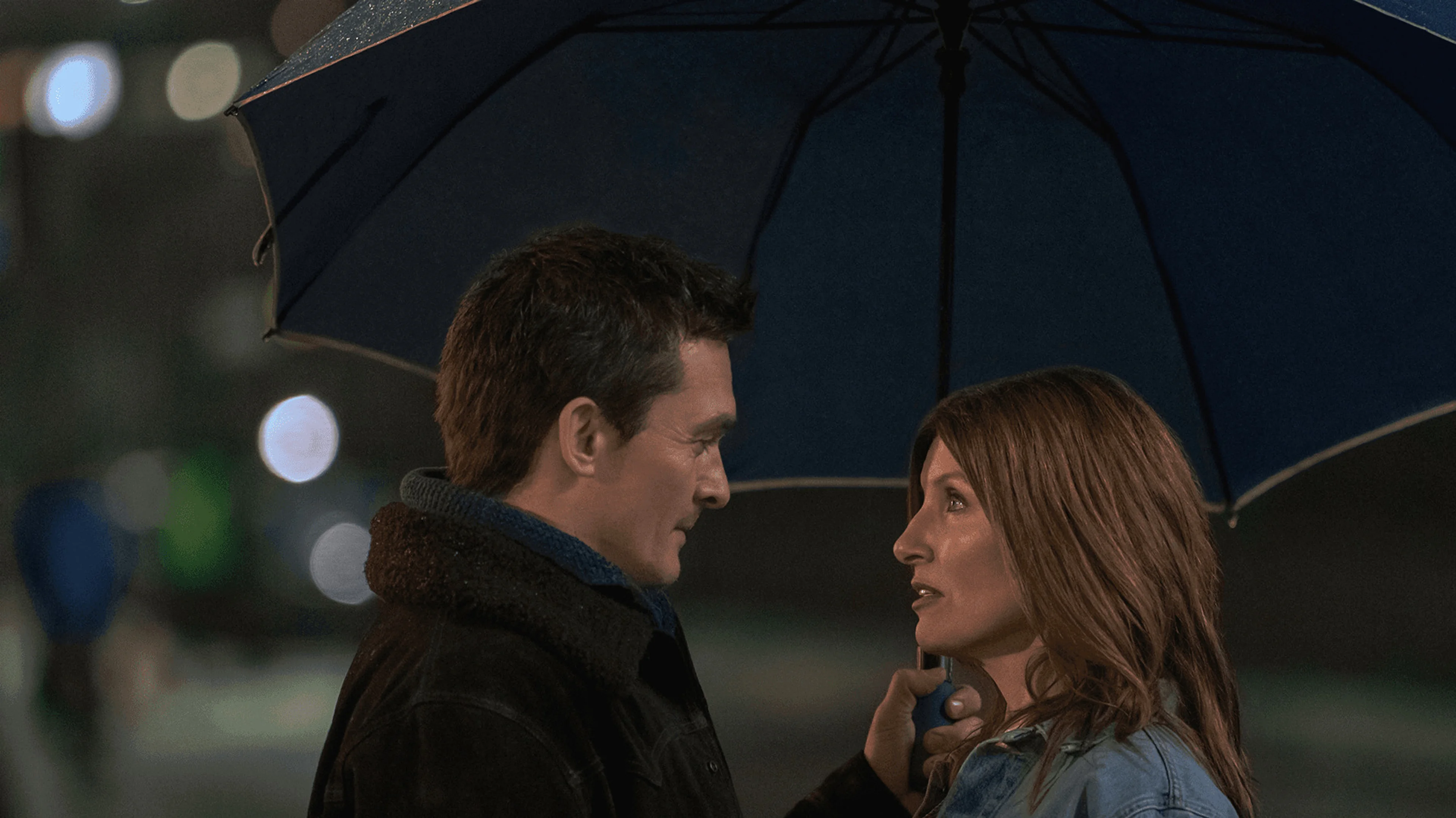 Rupert Friend as Patrick faces Sharon Horgan as Alex under an umbrella in YOUTH.