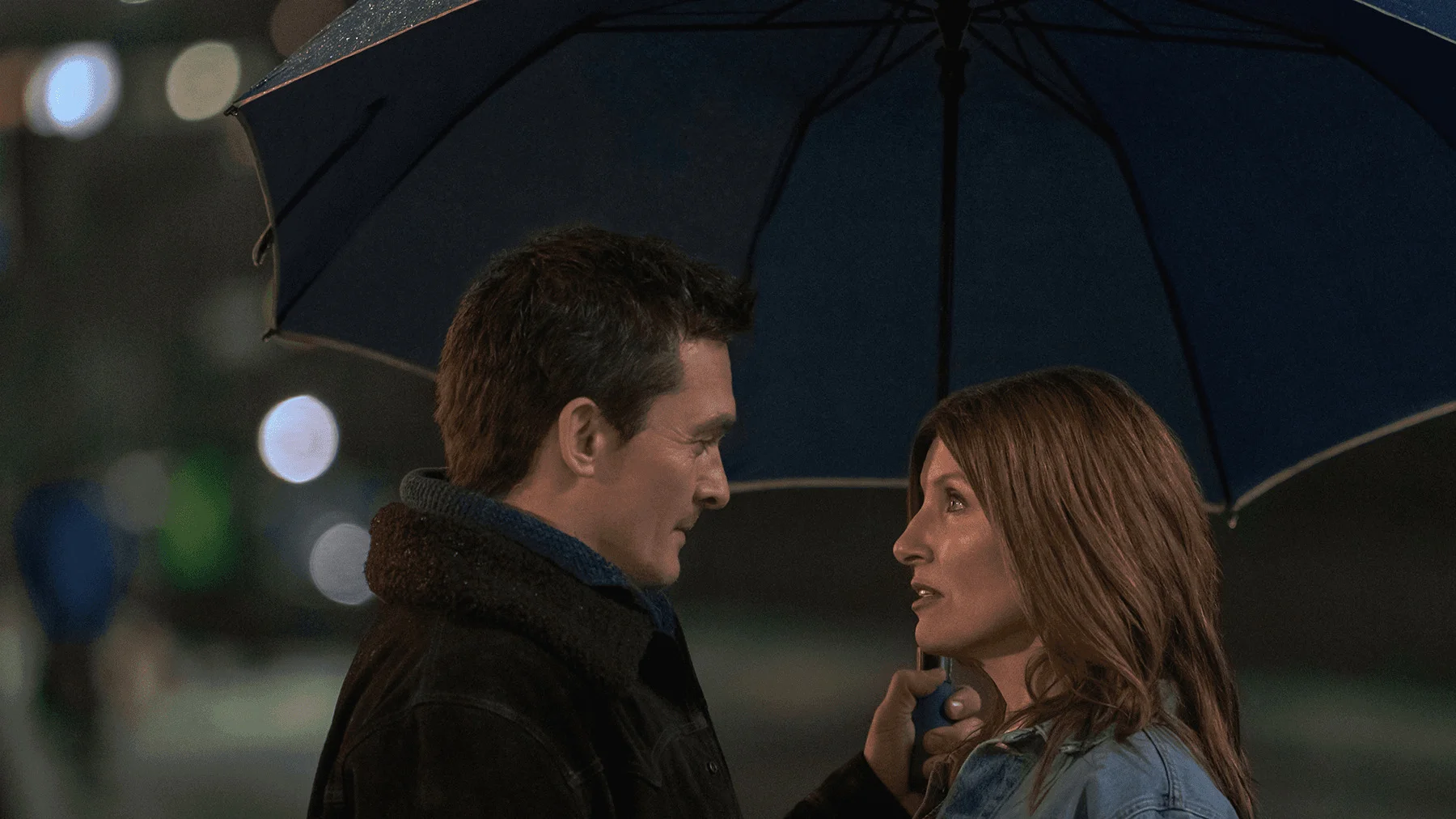 Rupert Friend as Patrick faces Sharon Horgan as Alex under an umbrella in YOUTH.