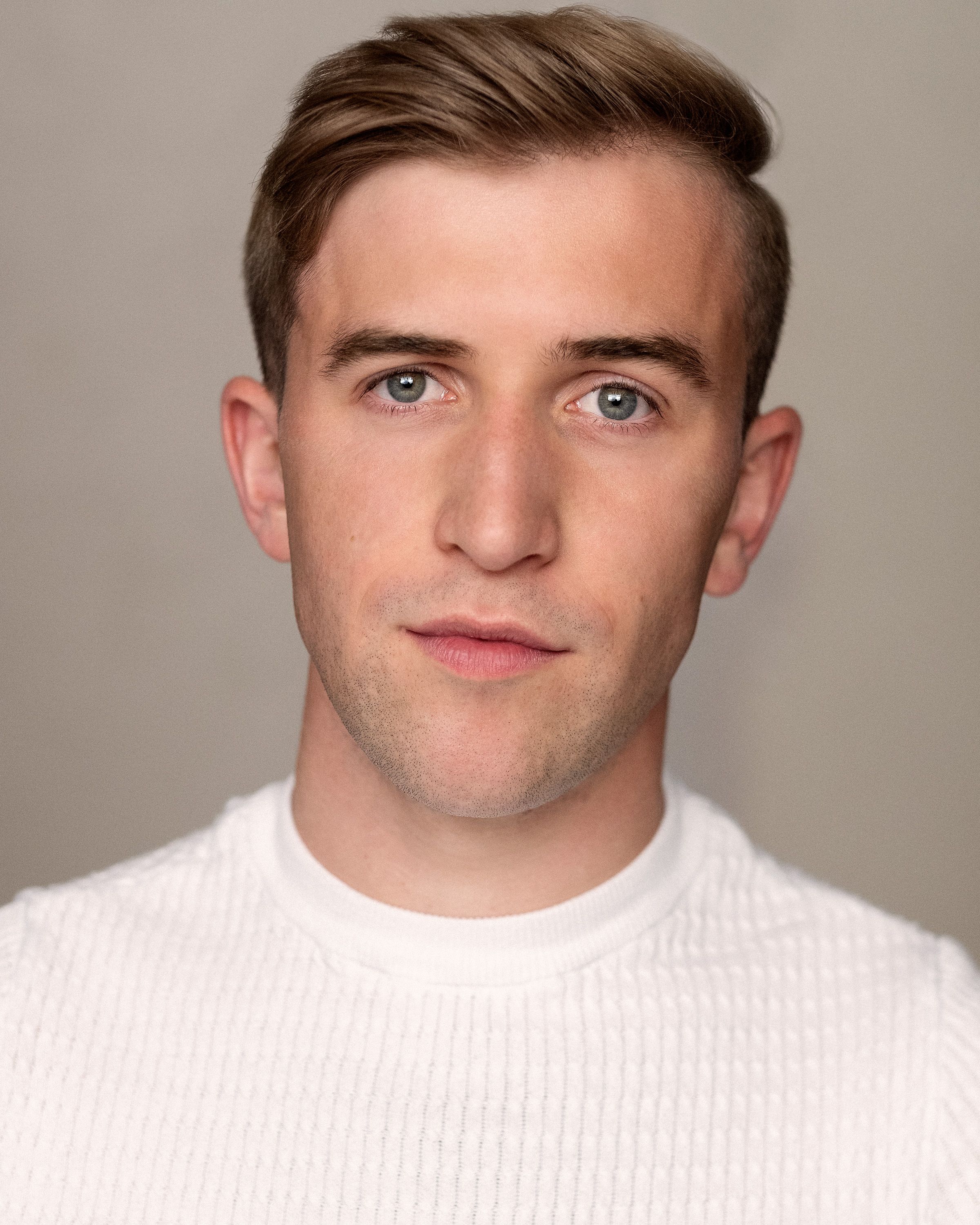 Callum Scott Howells looks at the camera wearing a white sweater.