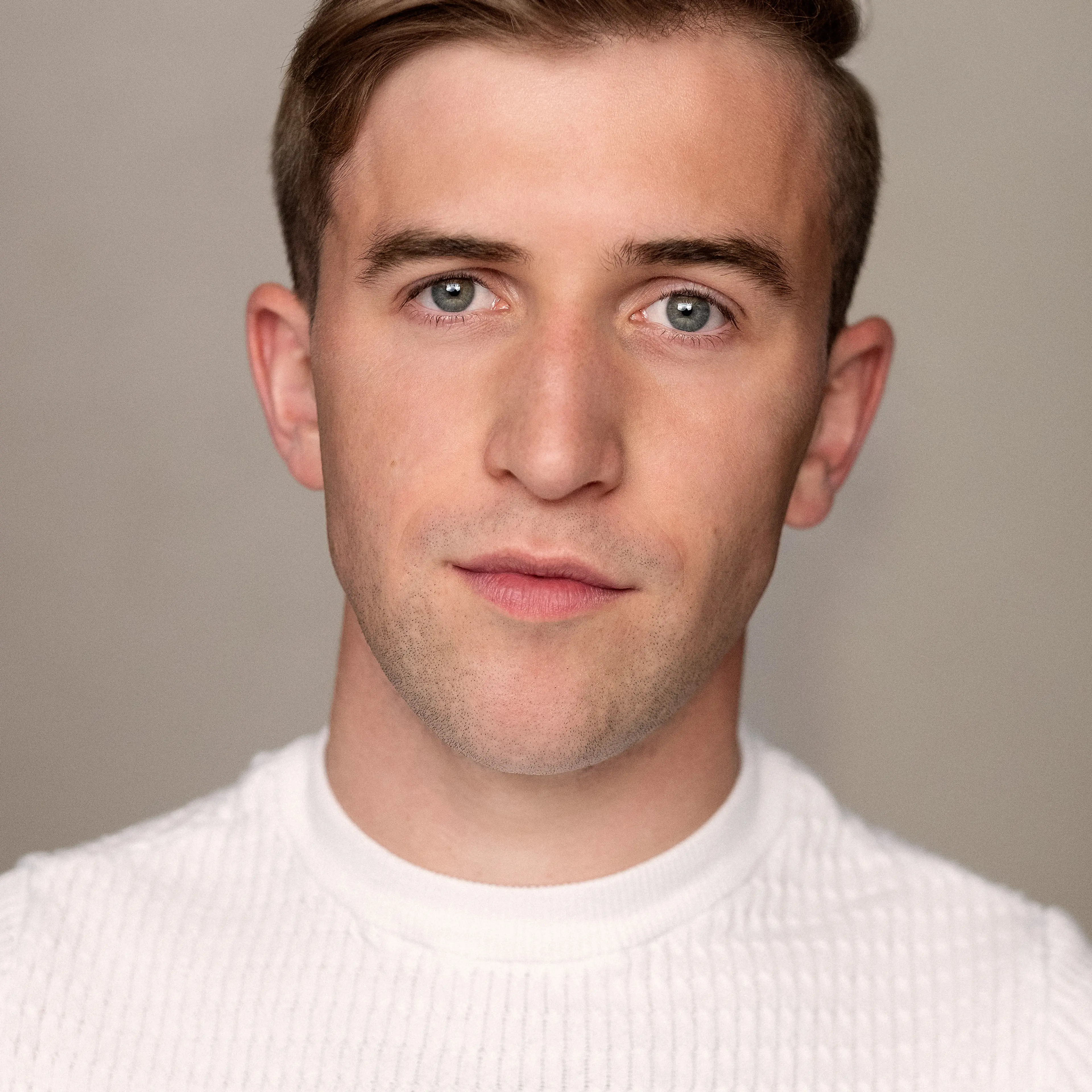Callum Scott Howells looks at the camera wearing a white sweater.