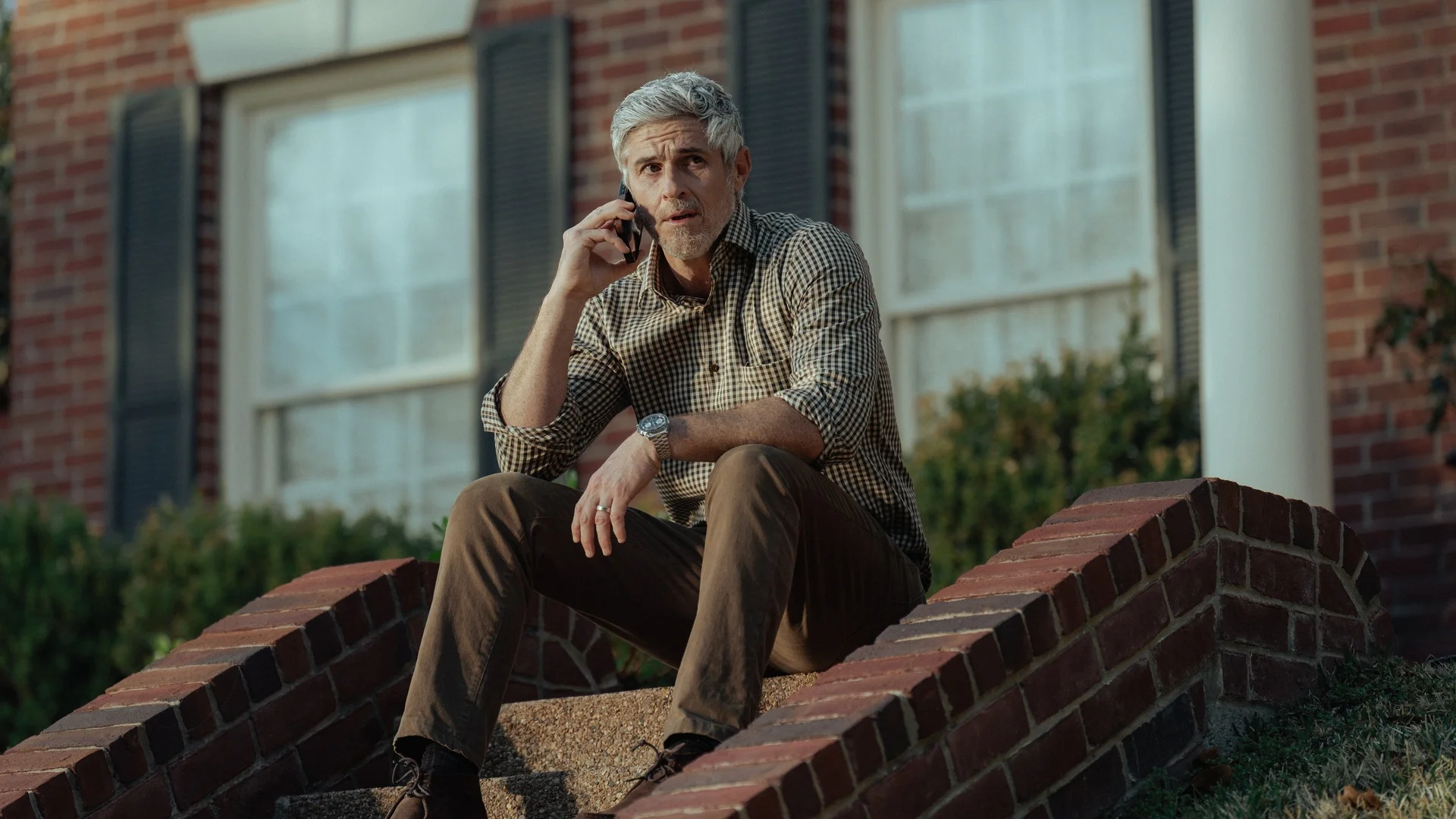 Dave Annable as Neal sits on outdoor steps while talking on a phone in Lioness Season 3.