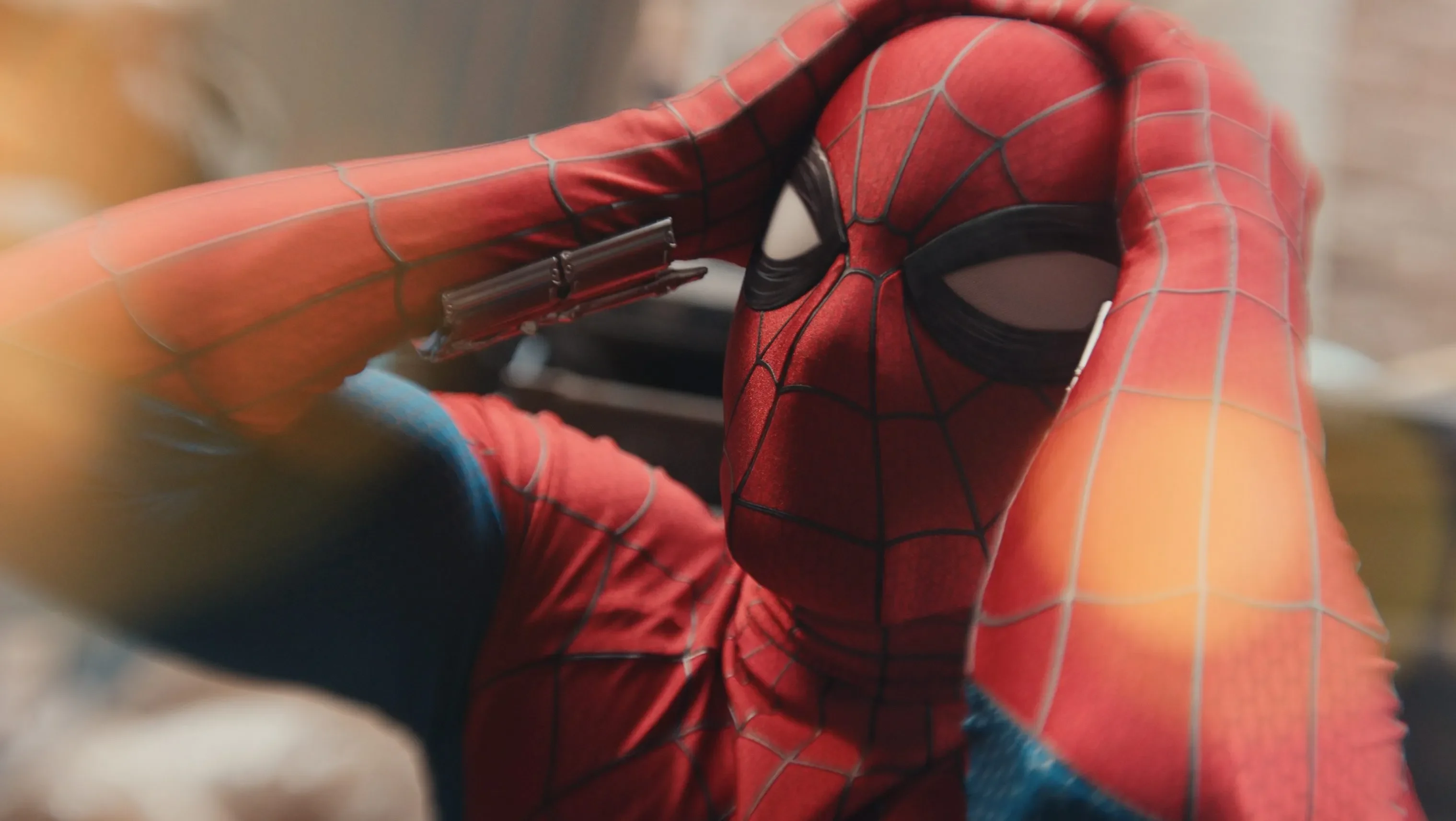 Spider-Man holds both hands against his head in a close shot