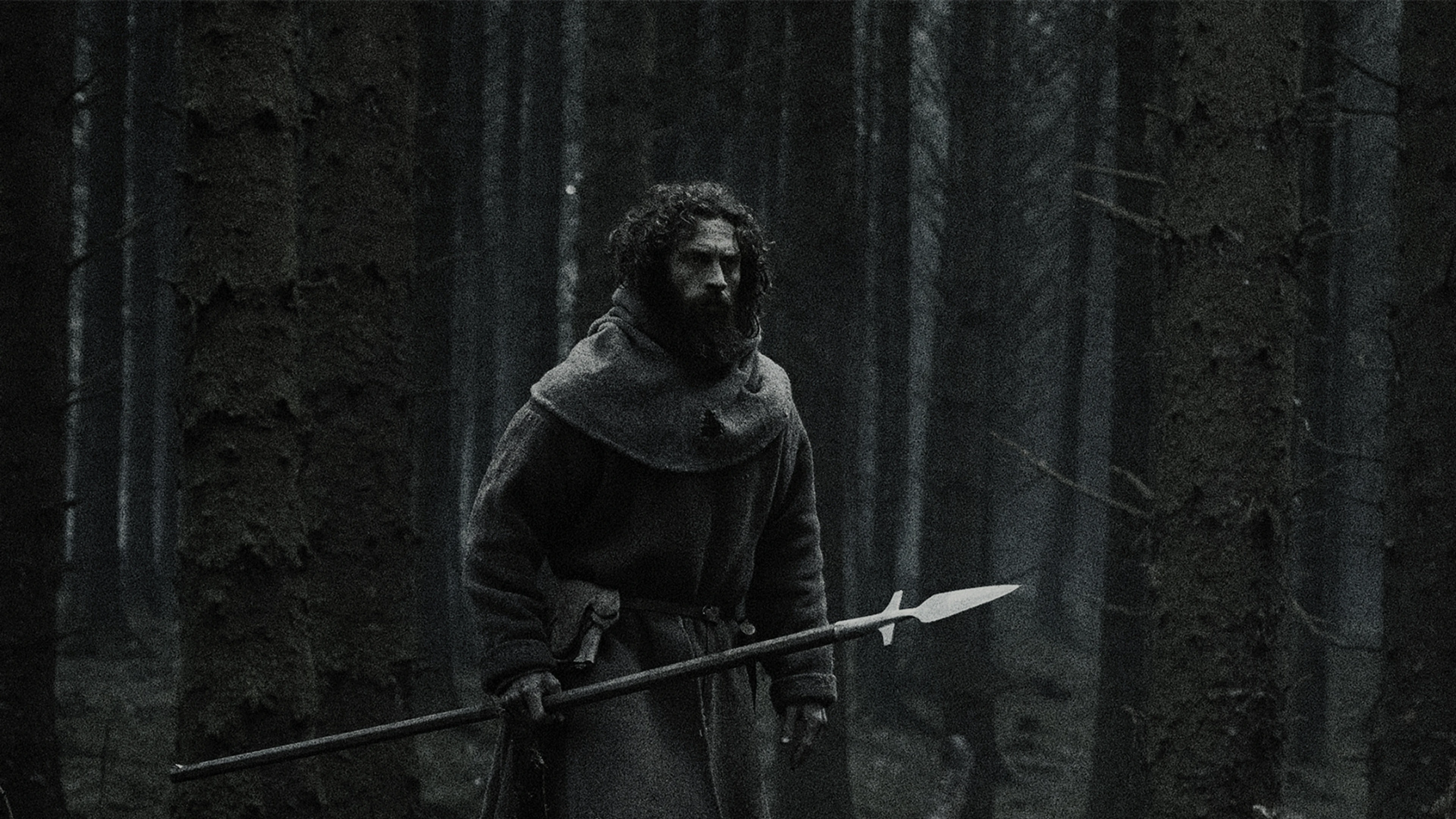 Aaron Taylor-Johnson stands in a dark forest holding a long spear in Werwulf.