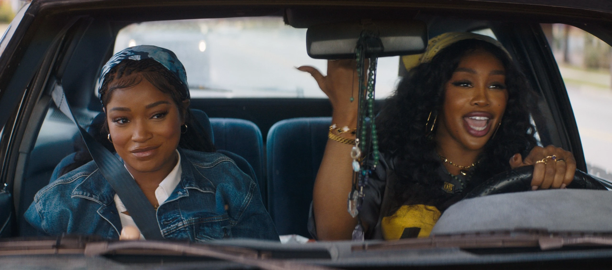 Keke Palmer sits in the passenger seat while SZA holds the wheel of their car.