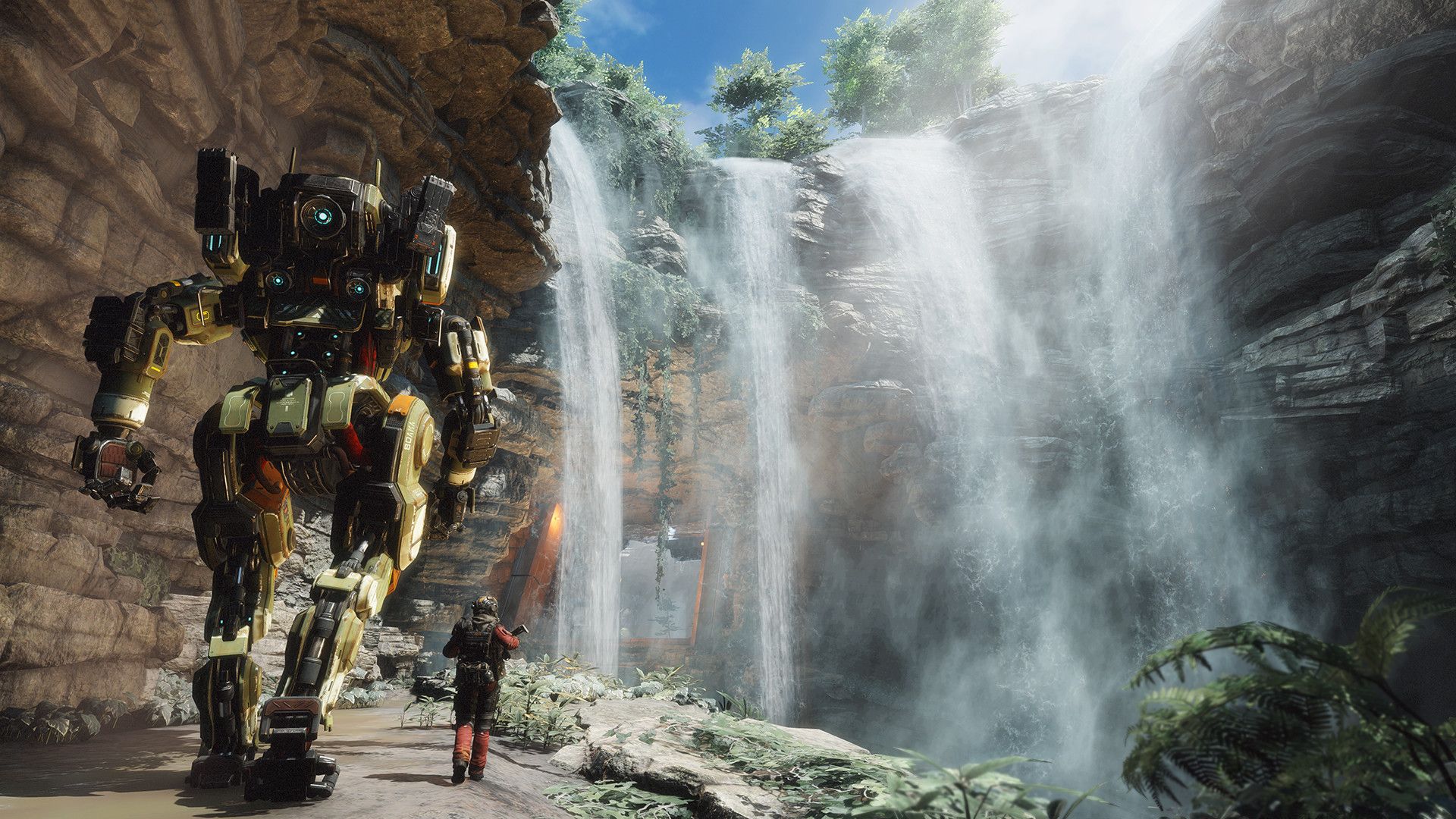 A Pilot stands beside the tall Titan BT near a waterfall.