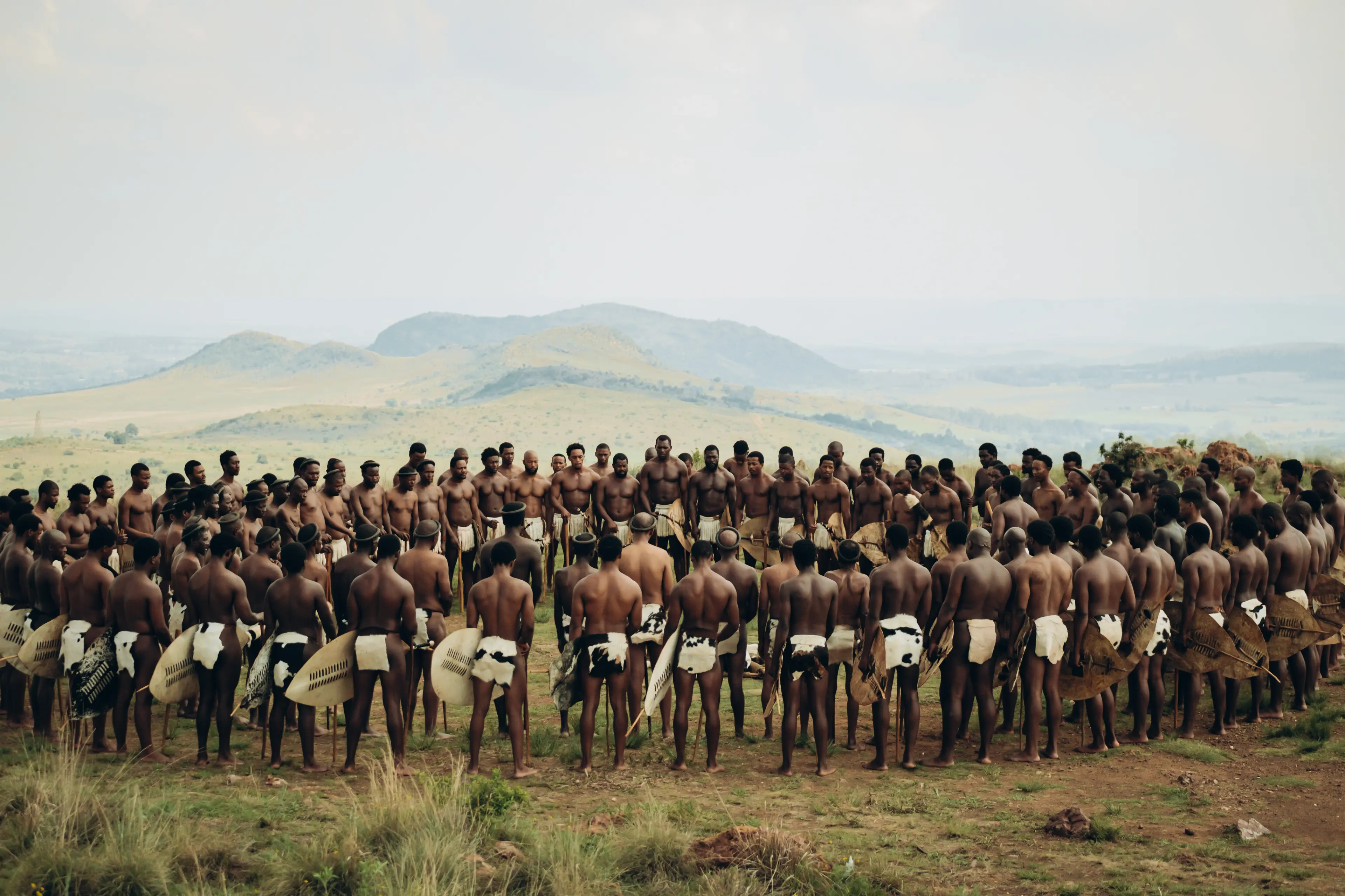A large group of Zulu men stands in a circle in a Shaka iLembe Season 3 publicity image.
