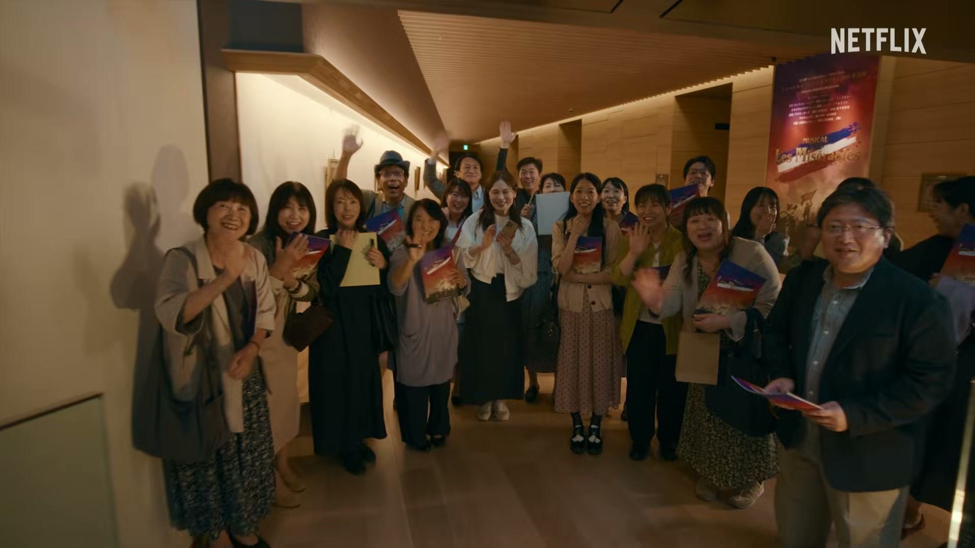 A large group of actors gathers inside a film production office.