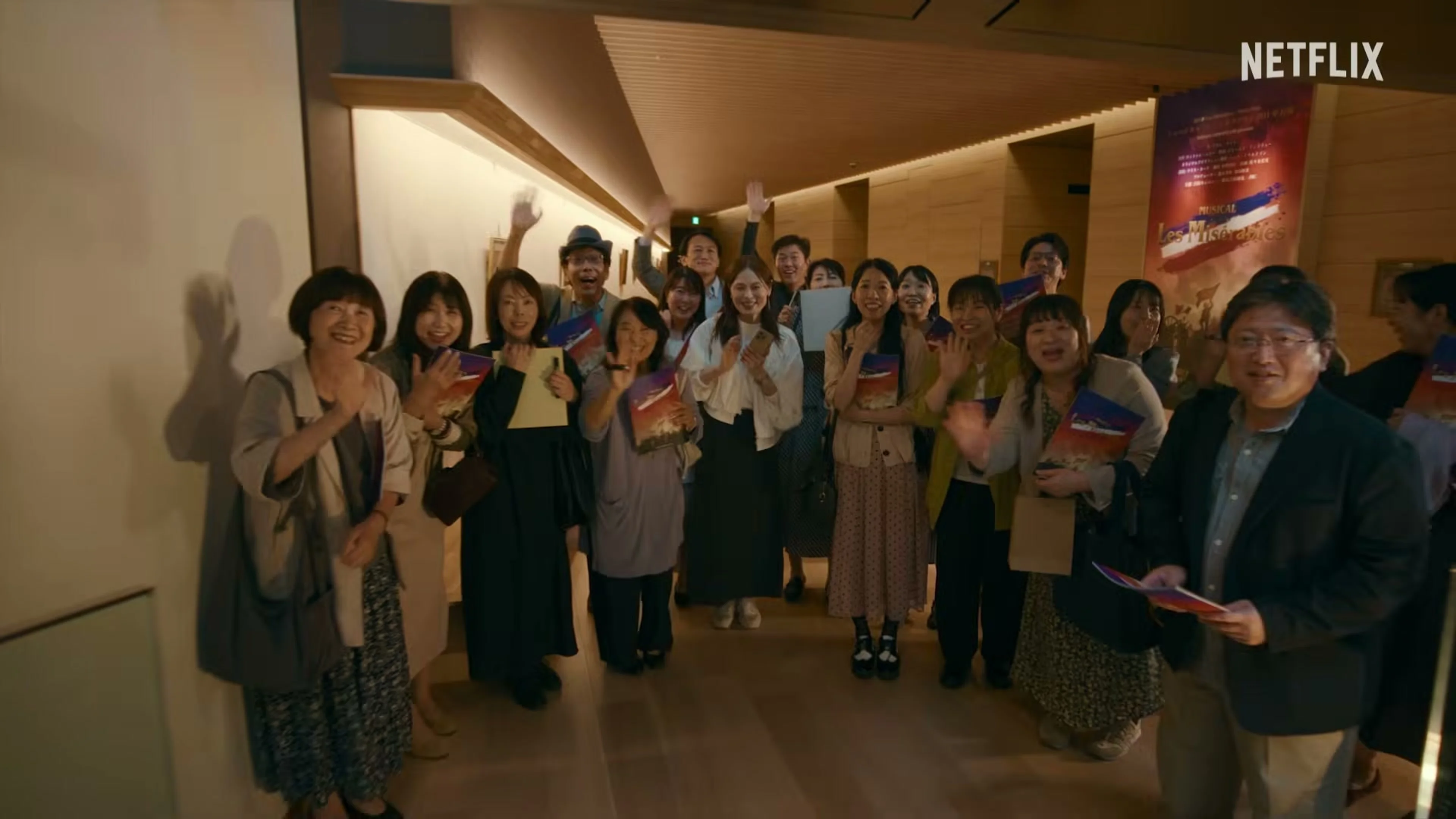 A large group of actors gathers inside a film production office.