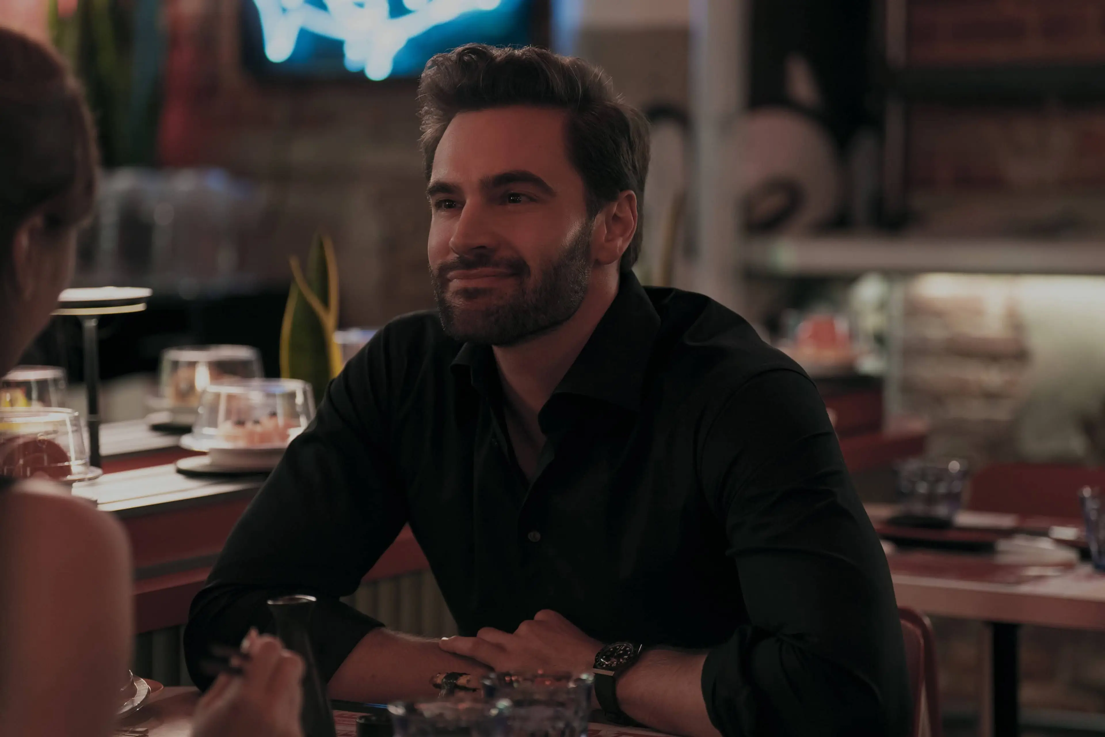 Adam smiles across a restaurant table.