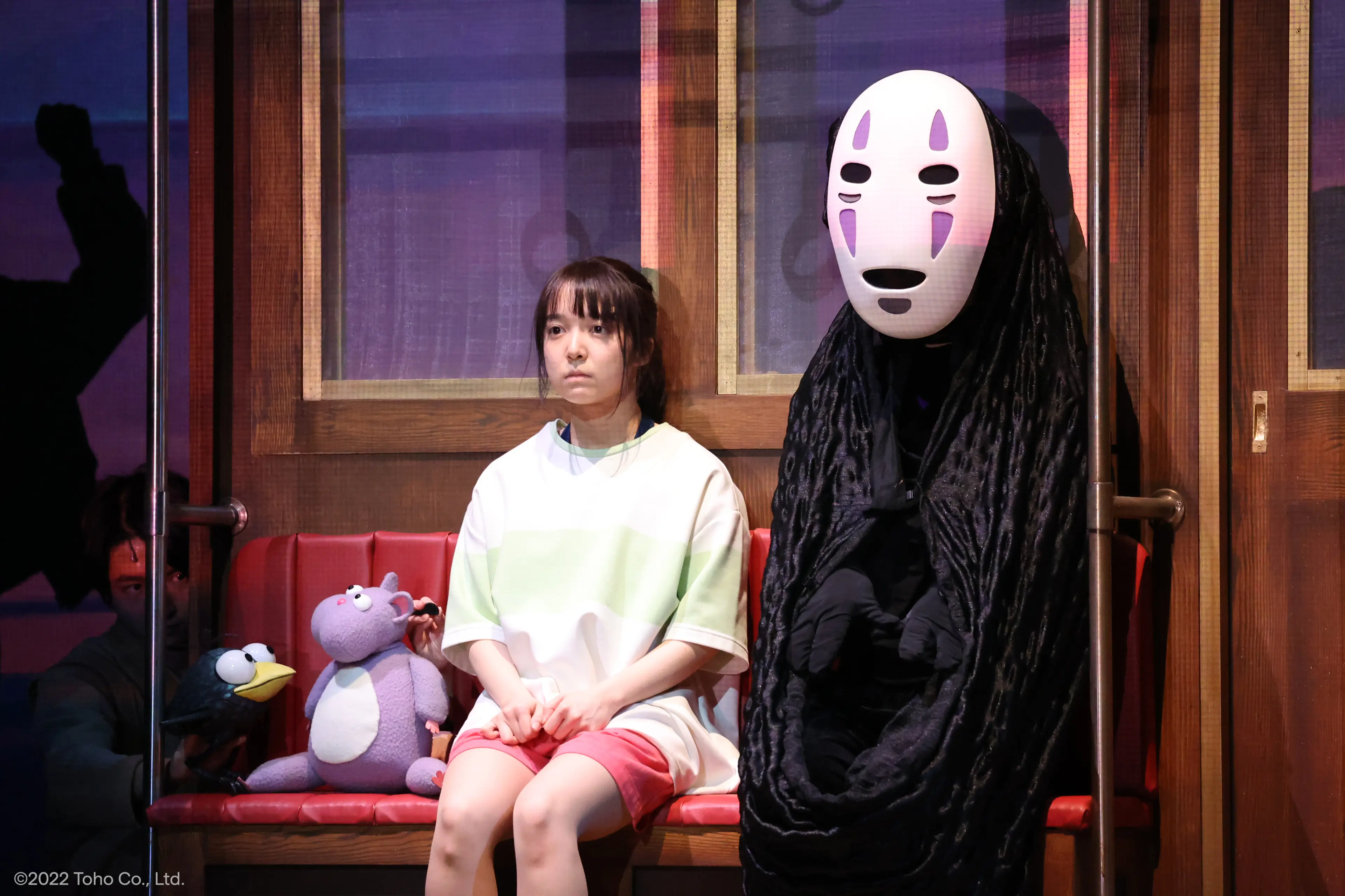 Mone Kamishiraishi as Chihiro sits beside No Face on the bathhouse set in Spirited Away: Live on Stage.