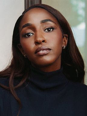 Ayo Edebiri wears a dark high-neck top with her hair falling over her shoulders.