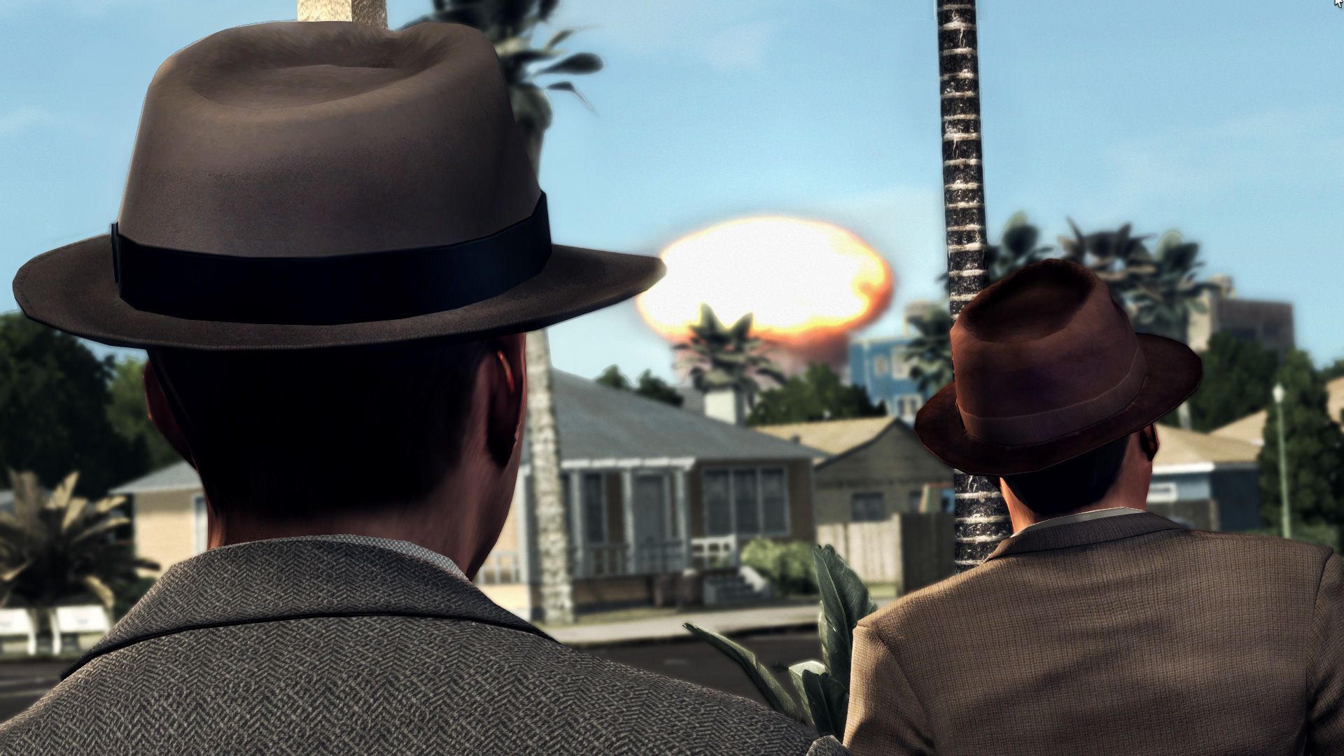 Two detectives in hats face an explosion behind a small building.