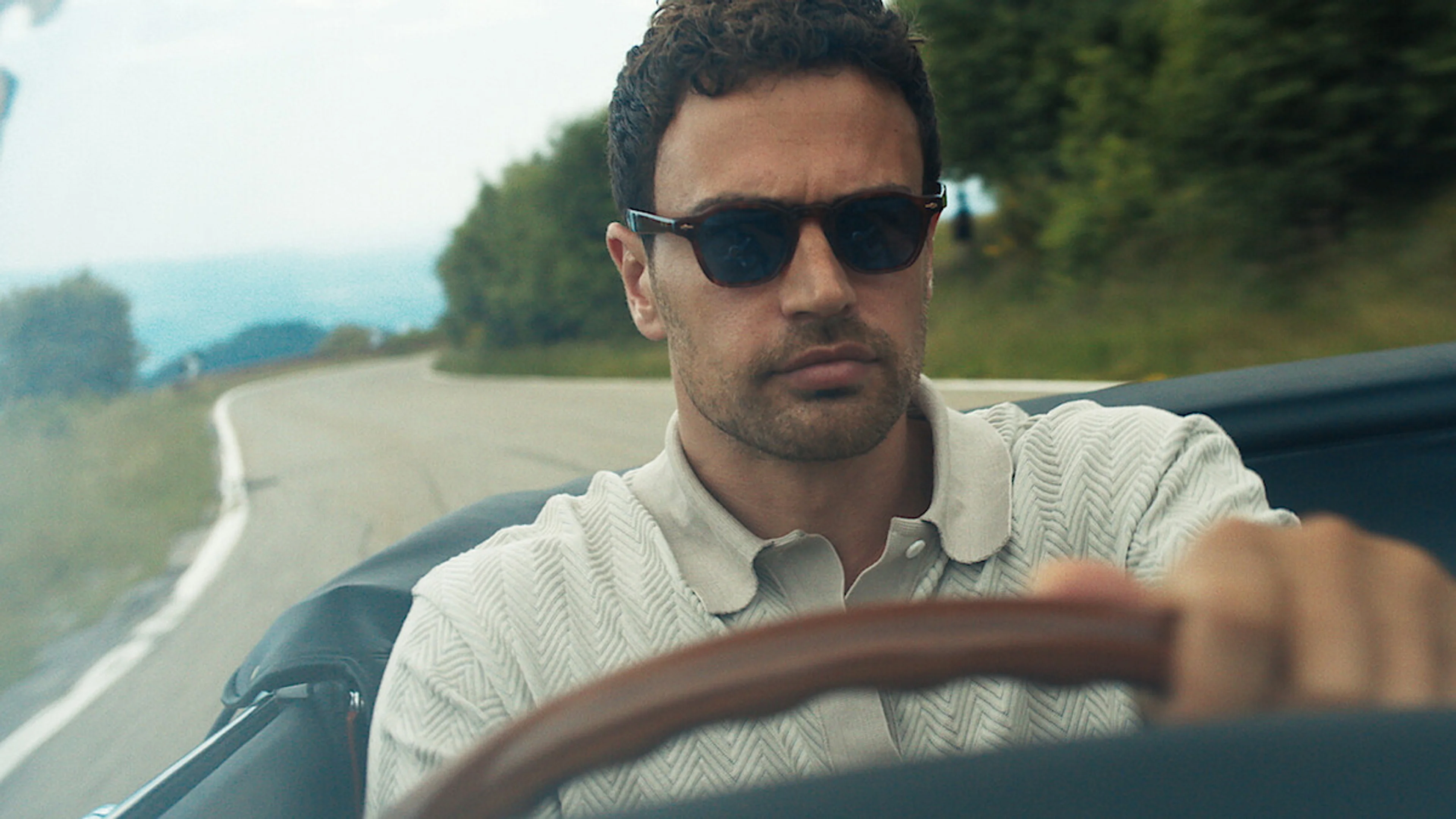 Theo James as Eddie Horniman drives a convertible in an official The Gentlemen Season 2 still.