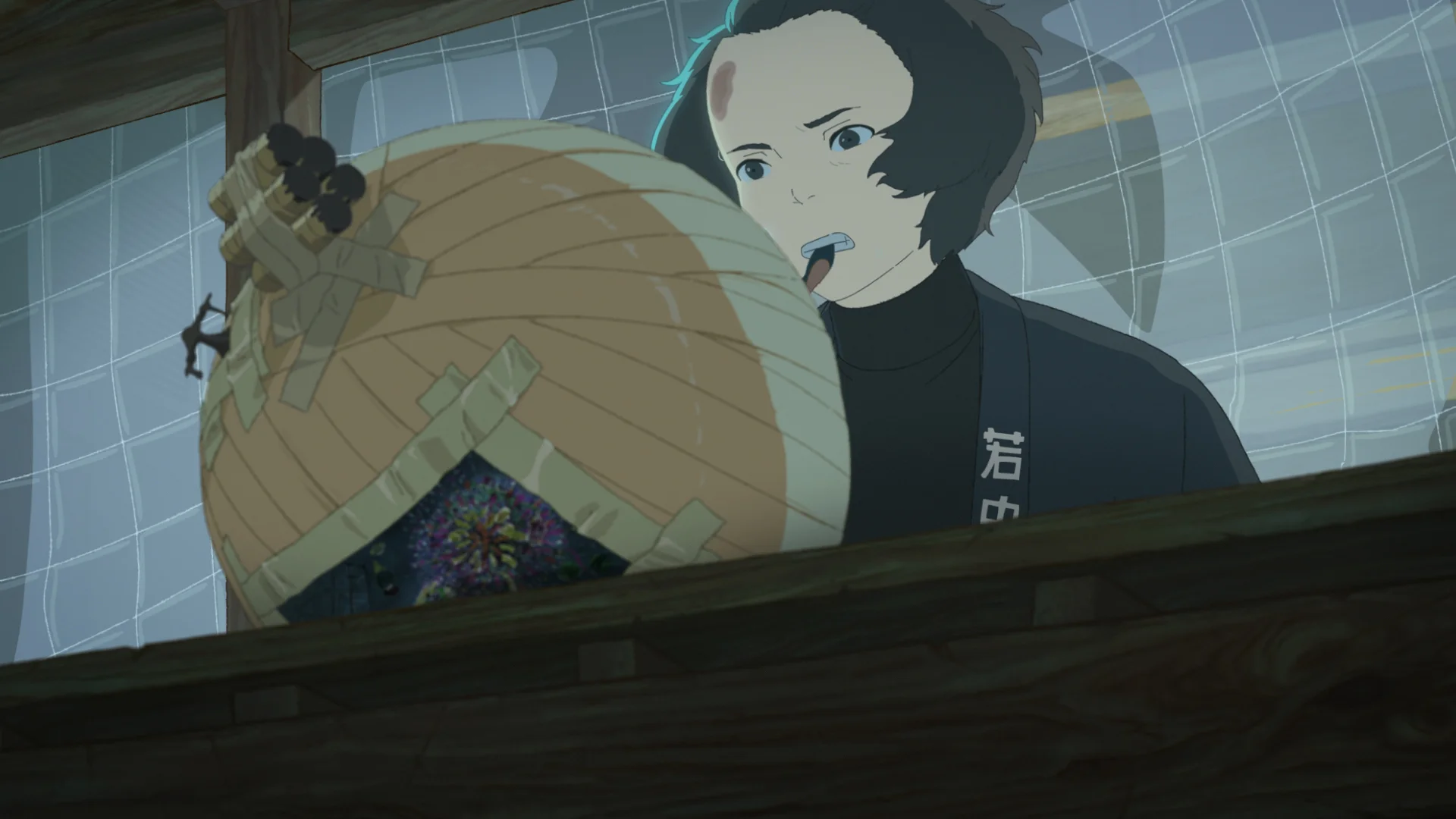 A bandaged young man in a dark coat works beside a large round paper shell.