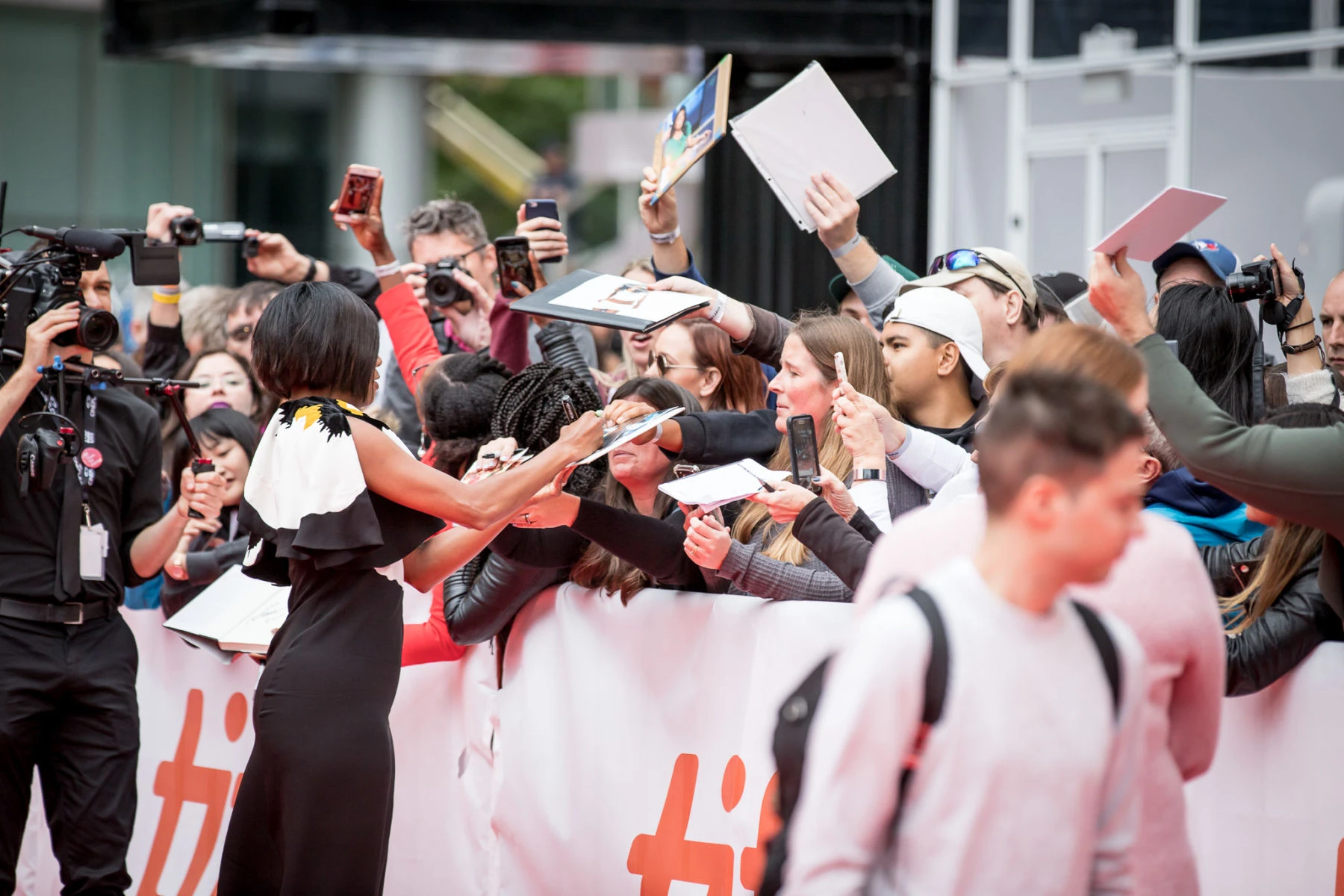 A guest greets fans and photographers on a Toronto International Film Festival red carpet.