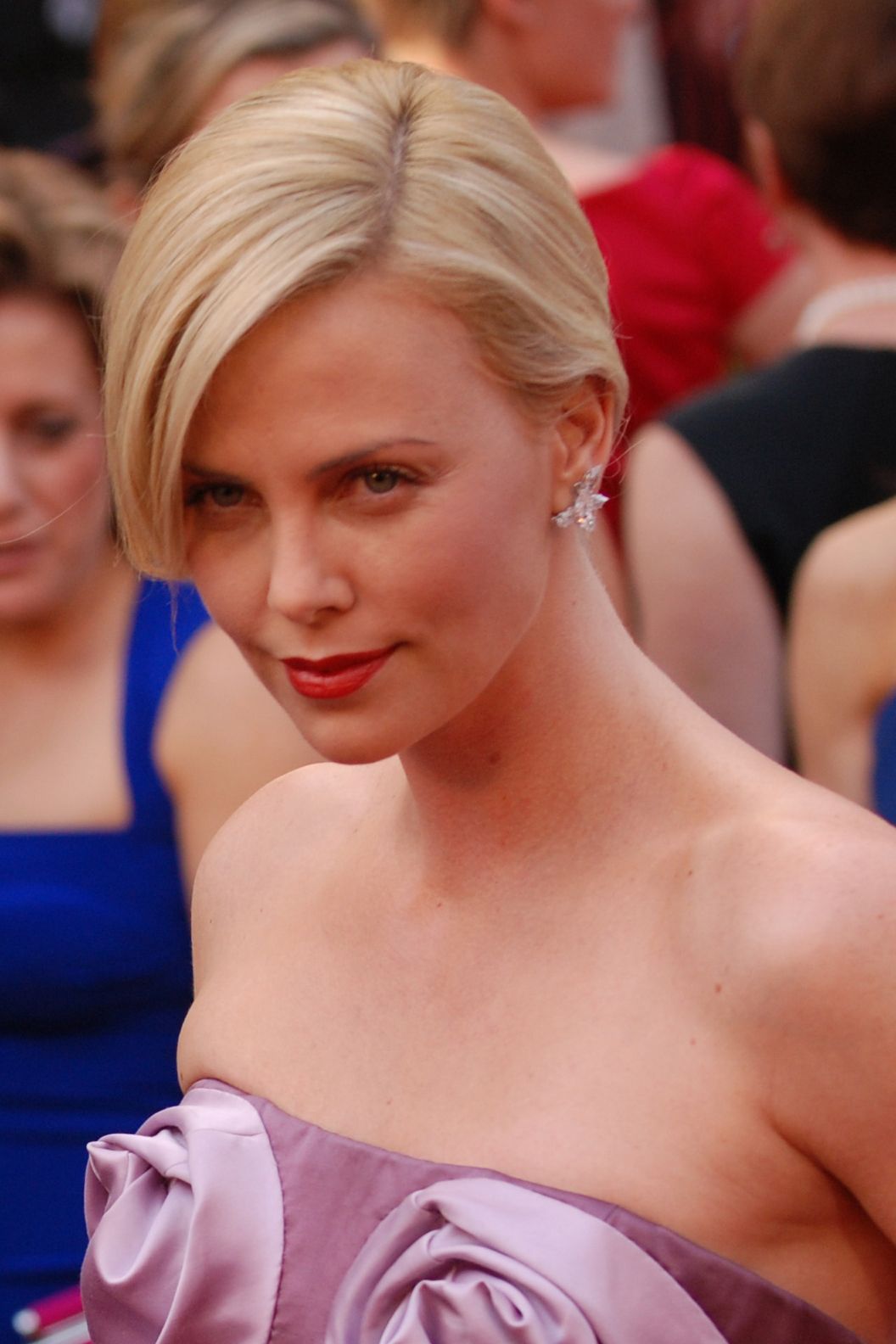 Charlize Theron at the 2010 Academy Awards, with blonde hair and red lipstick.