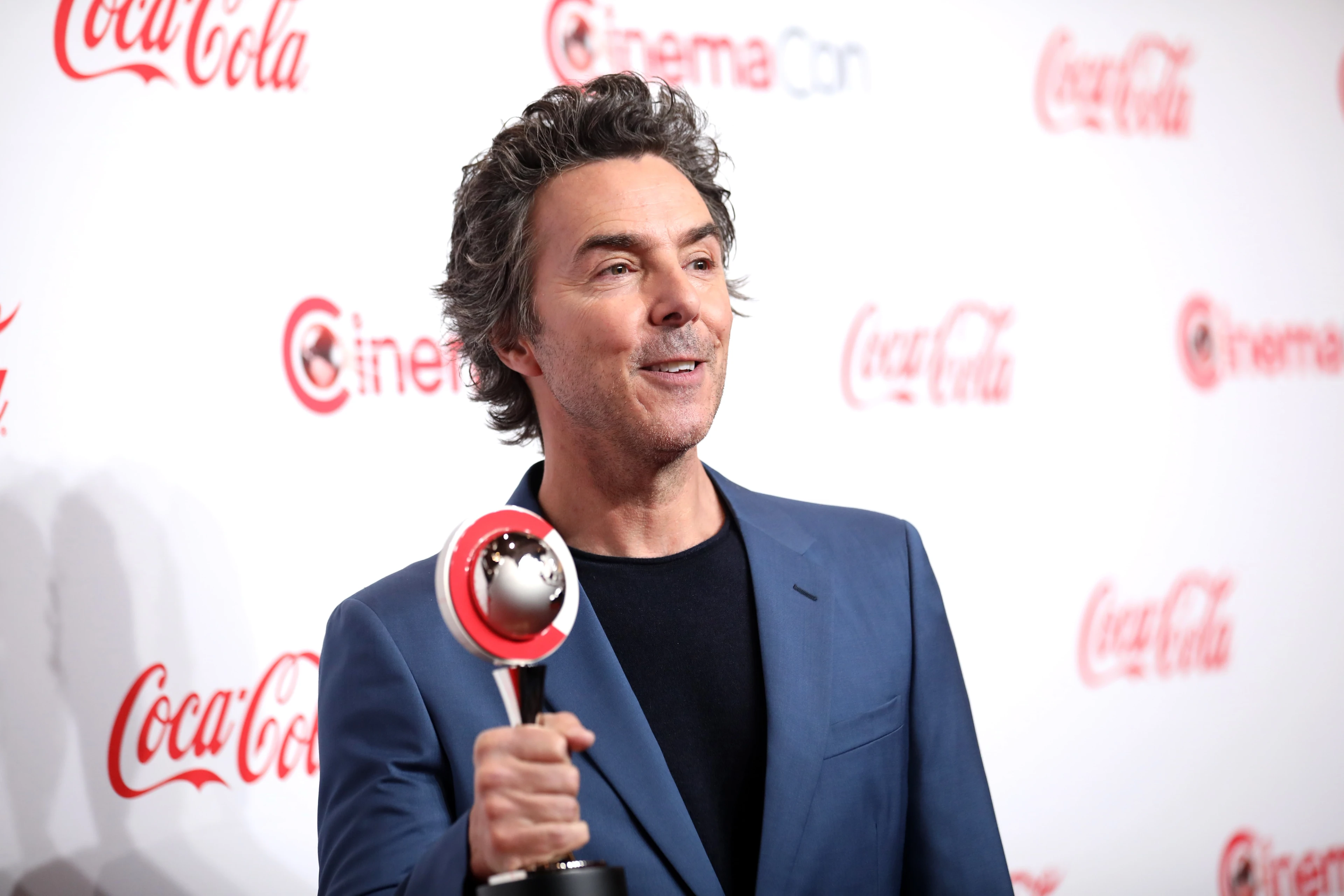 Shawn Levy holds a CinemaCon award on a red carpet in 2024.