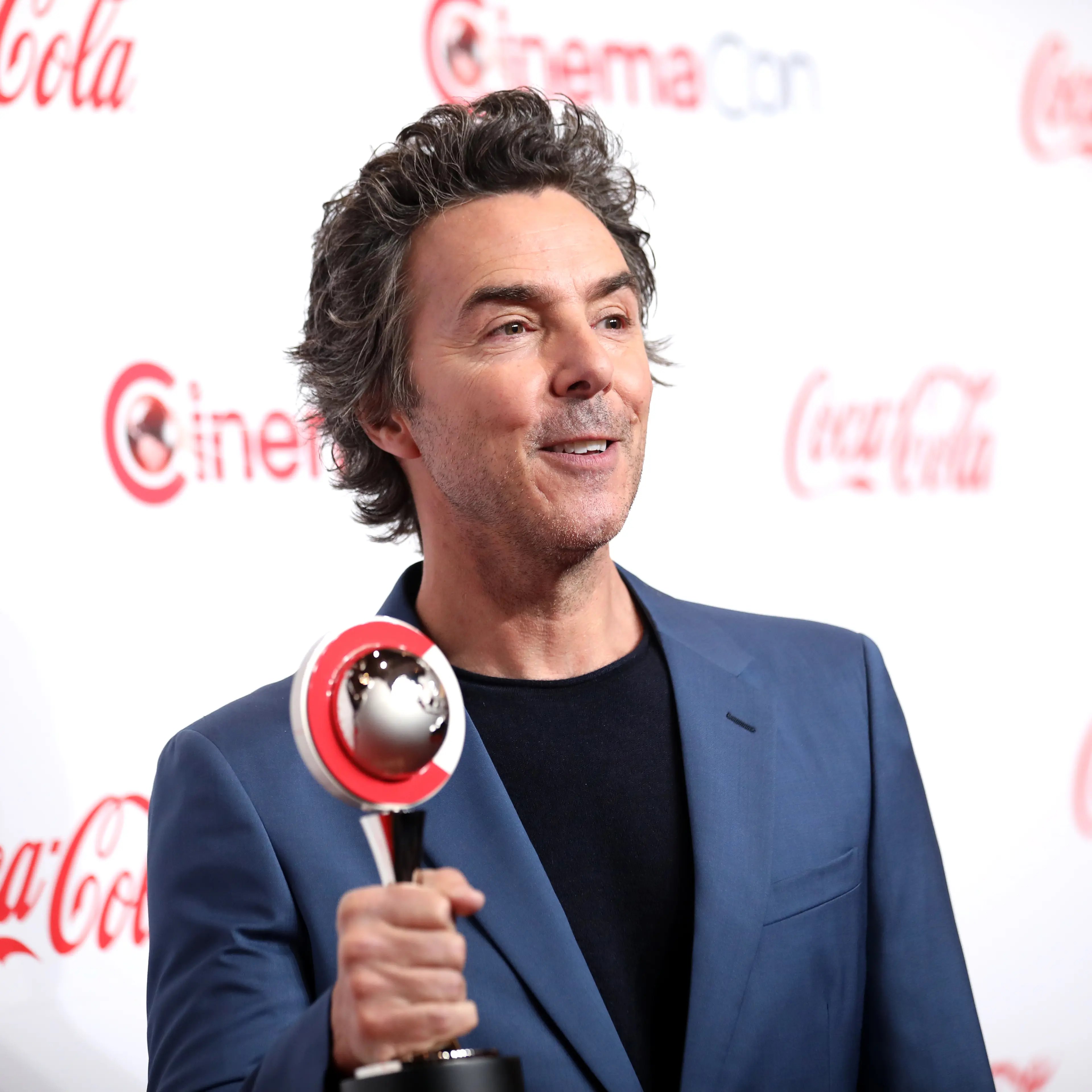 Shawn Levy holds a CinemaCon award on a red carpet in 2024.