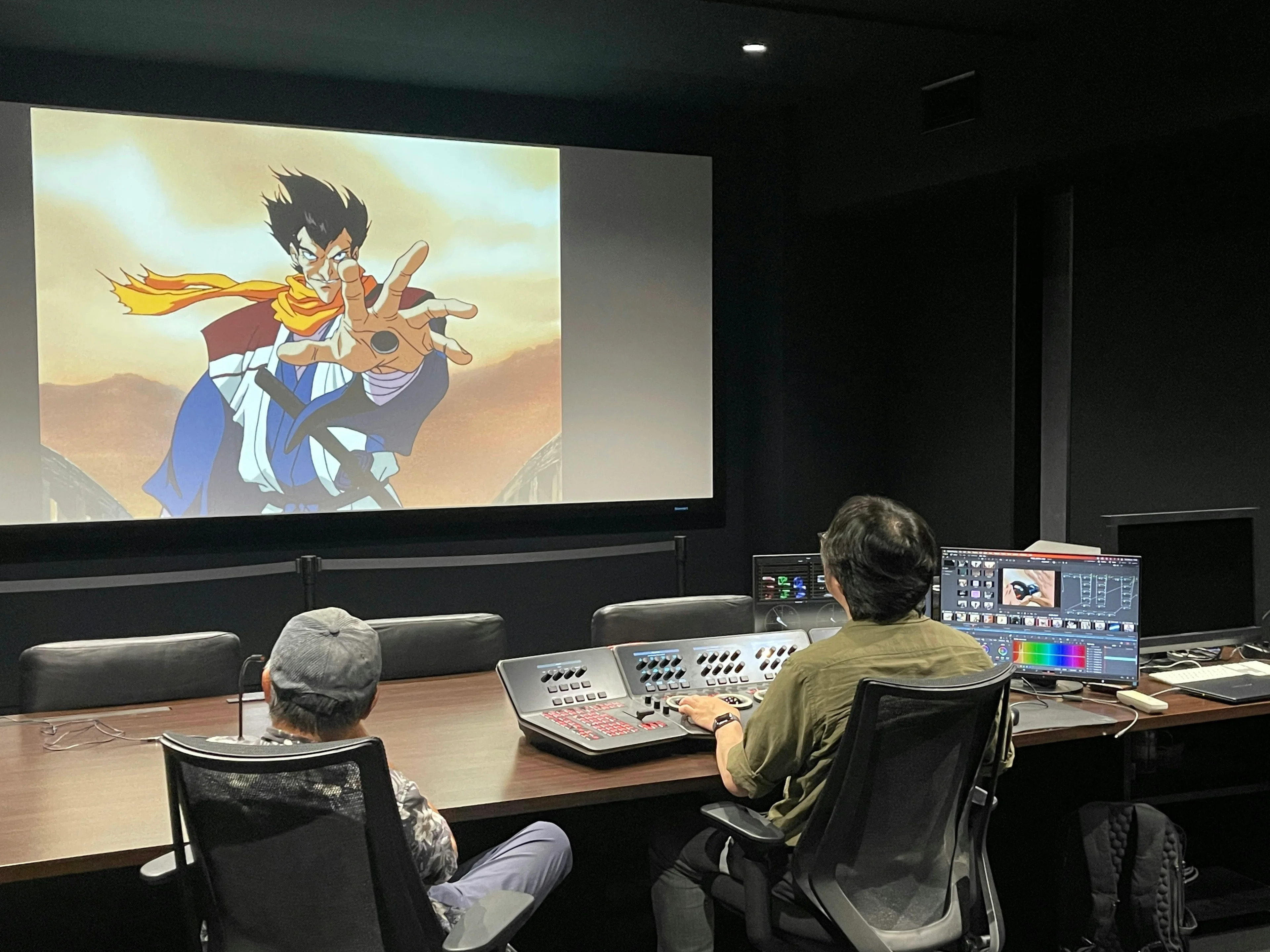 The restoration team reviews an animated character on a large screen beside monitors and color controls.
