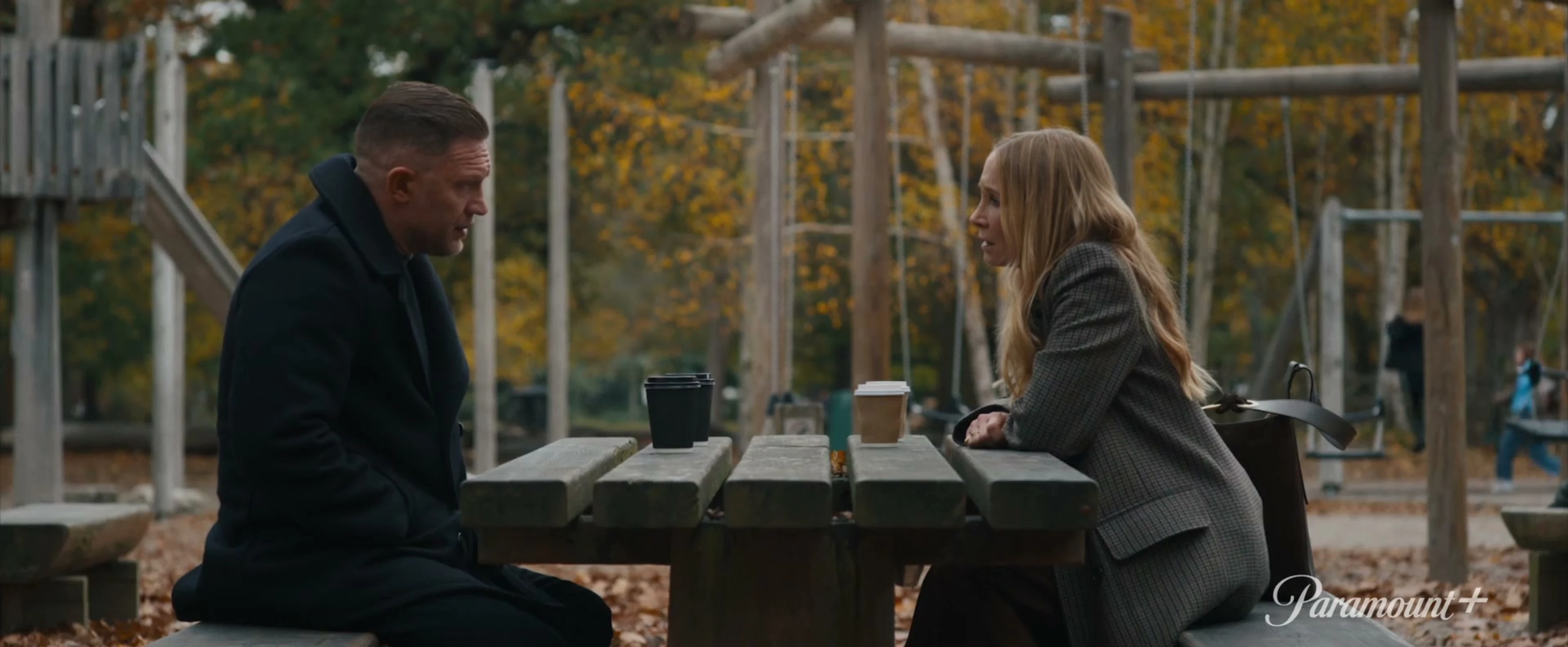 Harry da Souza and a woman speak across a picnic table in MobLand season two.