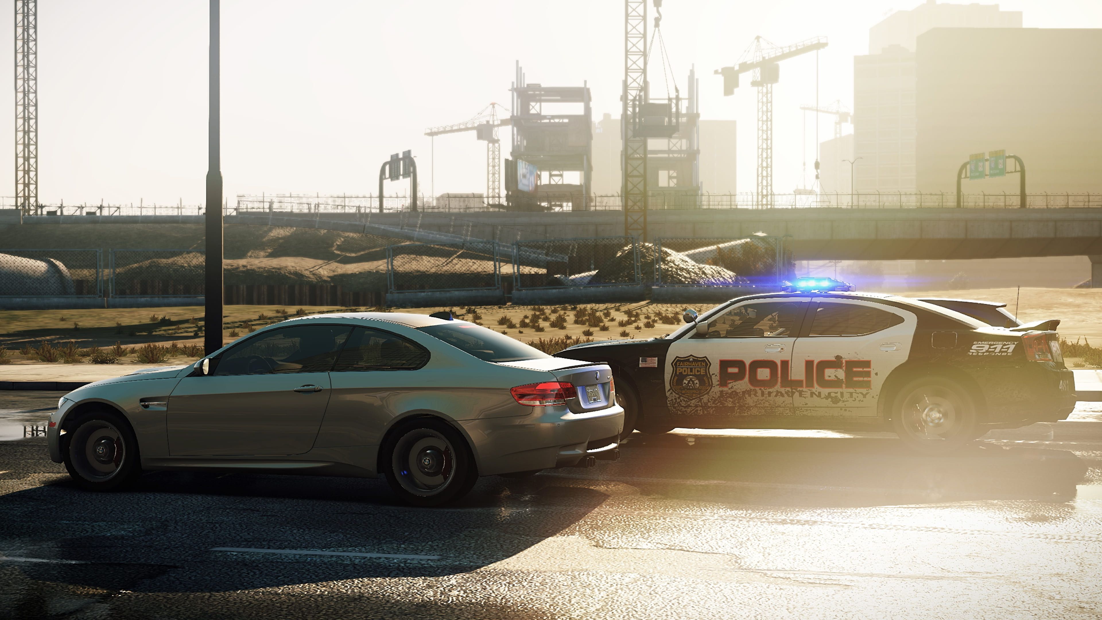 Silver BMW and a police car side by side on a Need for Speed: Most Wanted city road.