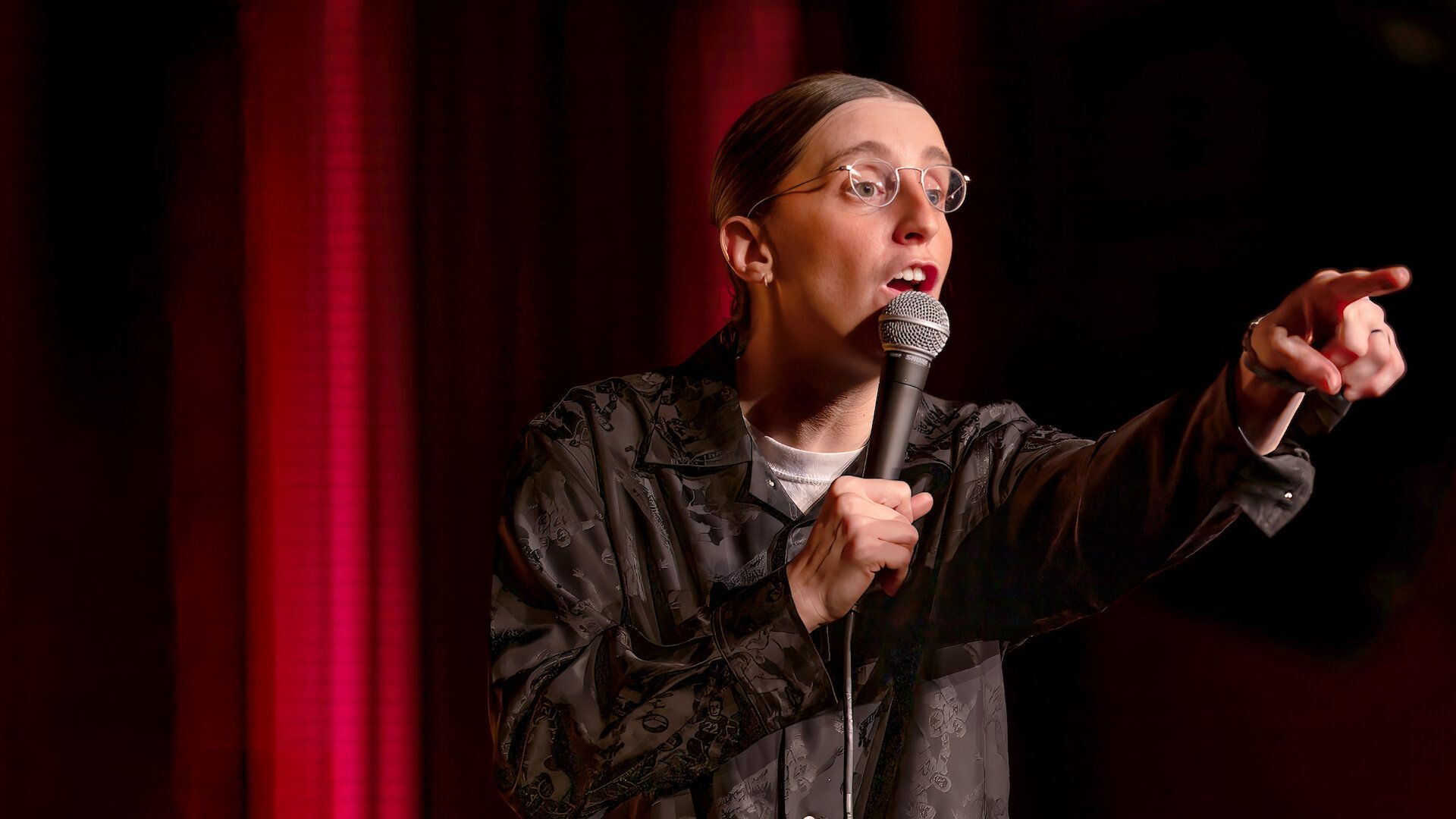 Robby Hoffman points into the audience while holding a microphone in her Netflix special Wake Up.