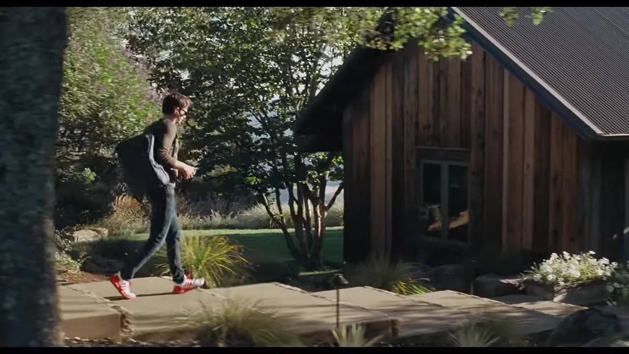 Andrew Garfield as Sam Altman walks outside a modern house in Artificial.