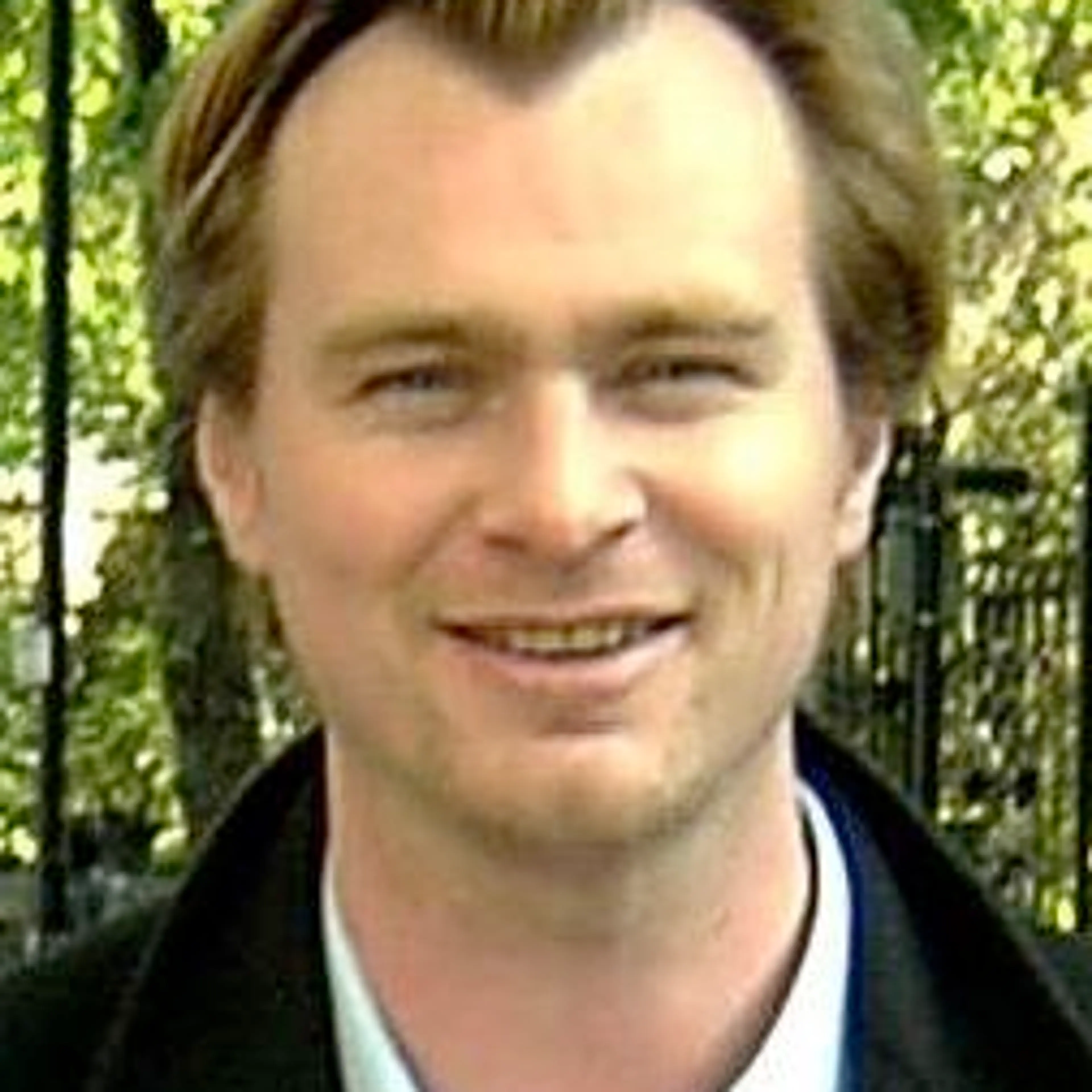 Christopher Nolan smiles in an outdoor portrait.