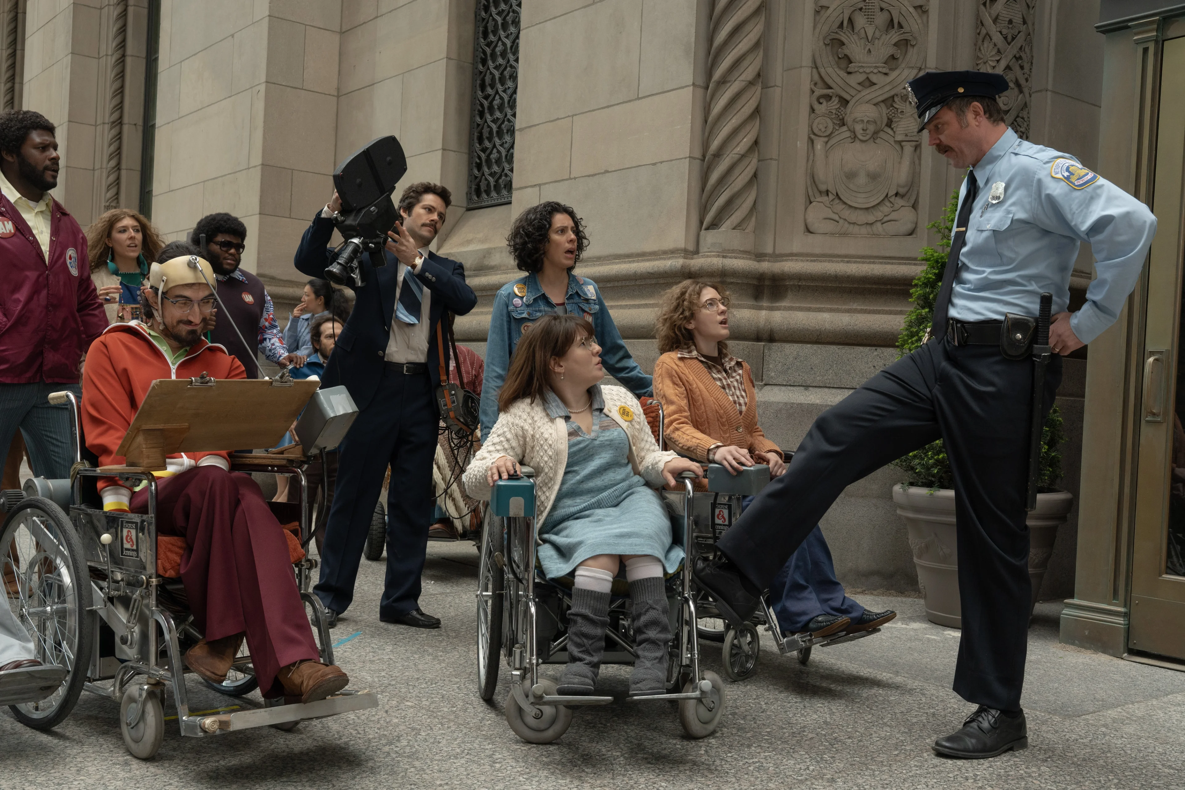 Disabled activists and allies face a police officer at a building entrance in Being Heumann.