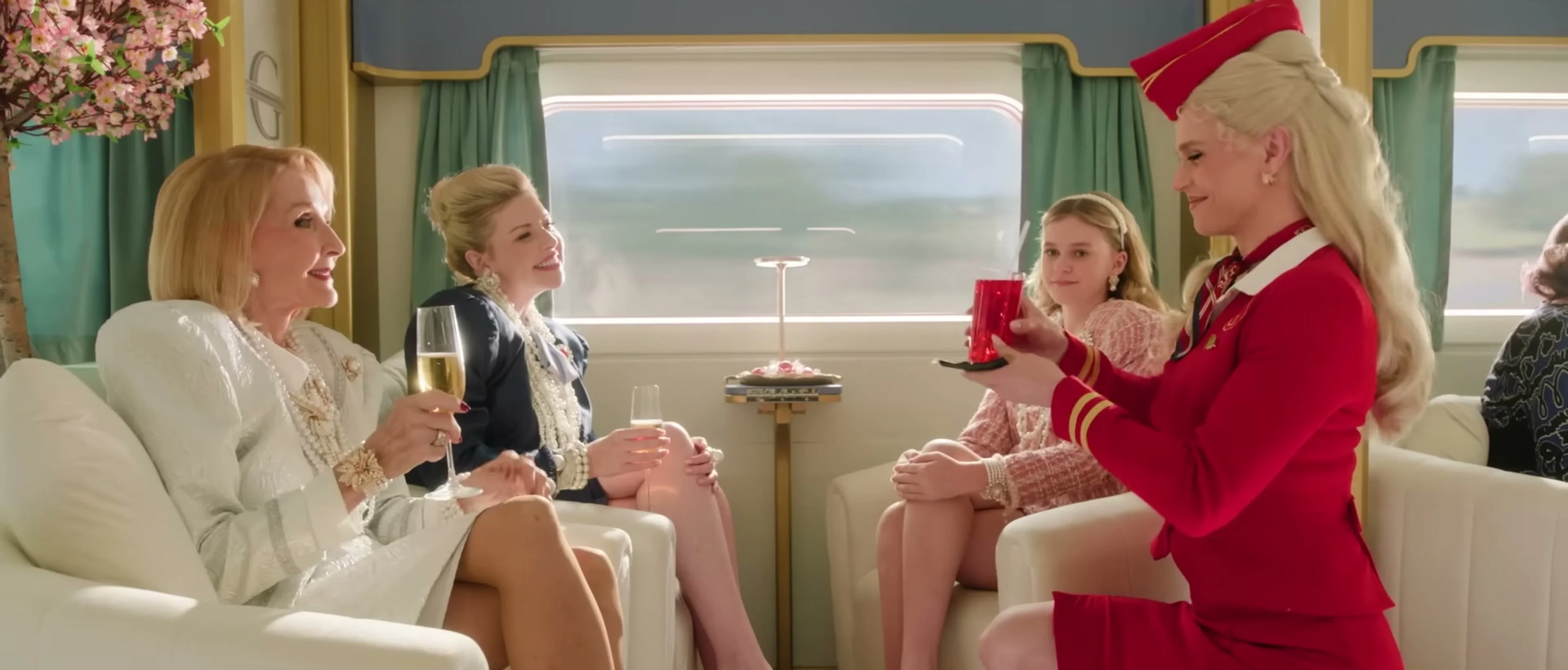 First-class passengers and stewardesses sit together in a luxury train carriage.