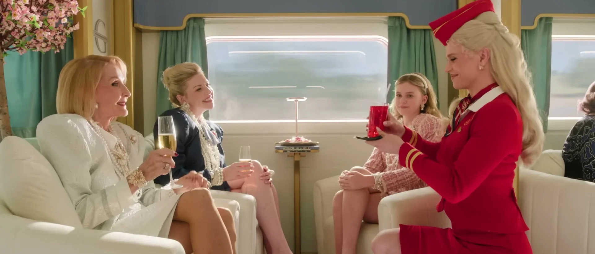 First-class passengers and stewardesses sit together in a luxury train carriage.