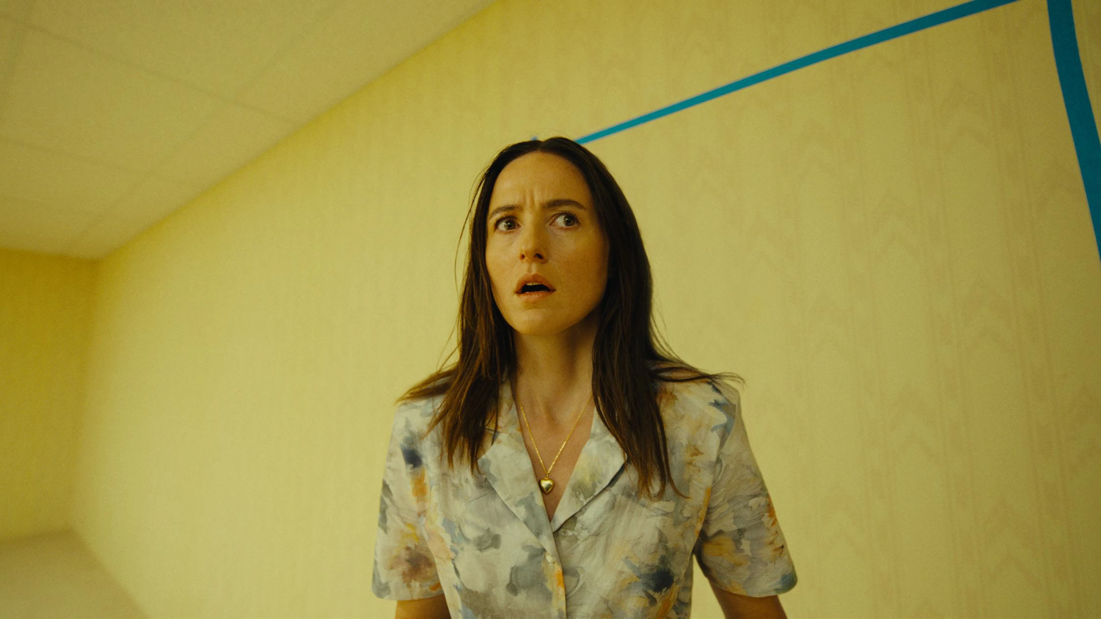 Mary stands beside a blue outline of a doorway on a yellow wall.