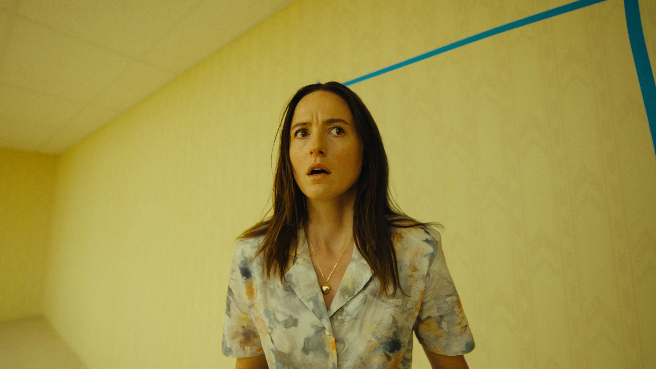 Mary stands beside a blue outline of a doorway on a yellow wall.