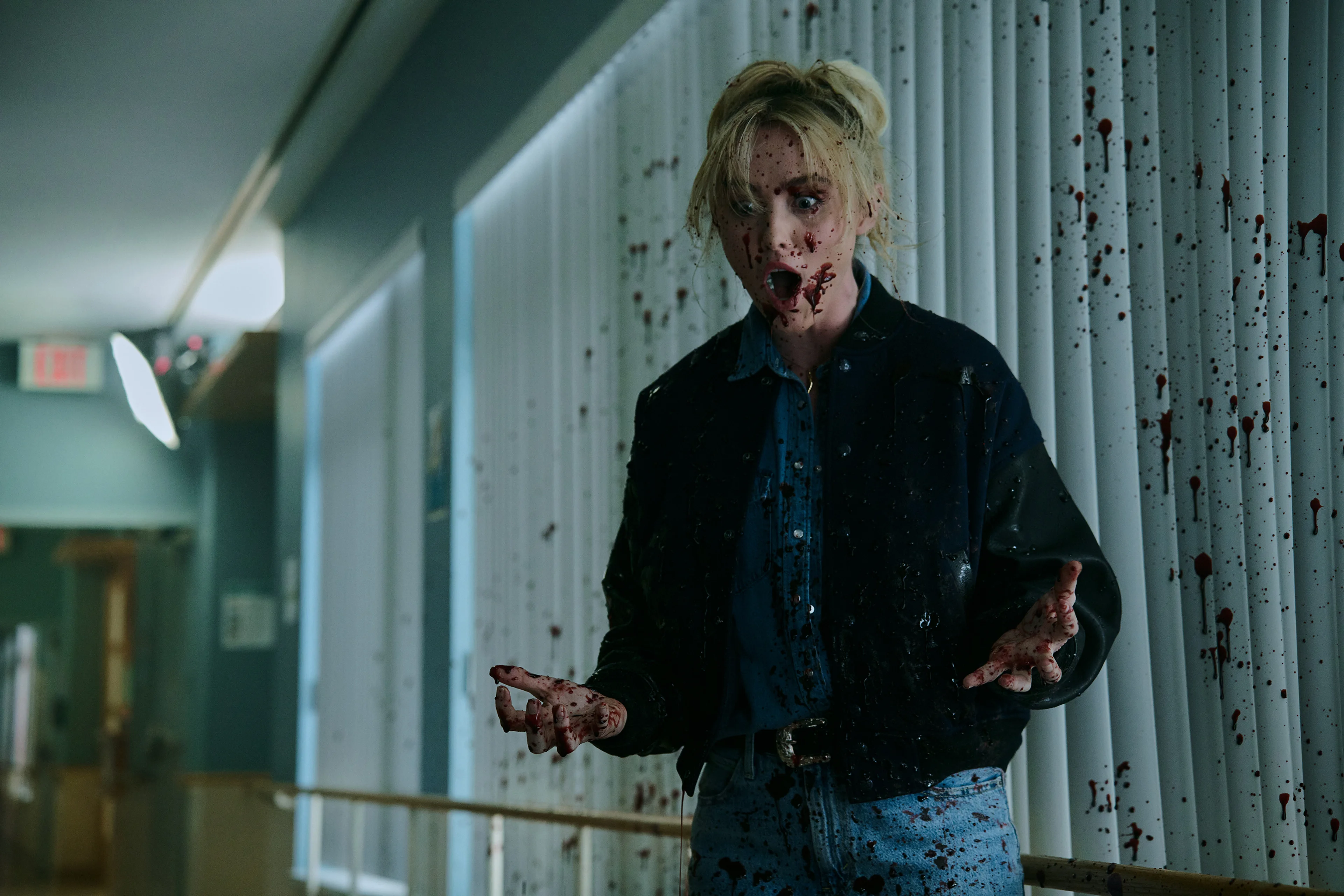 Faith looks shocked, with blood splashed across her face and the white wall behind her.