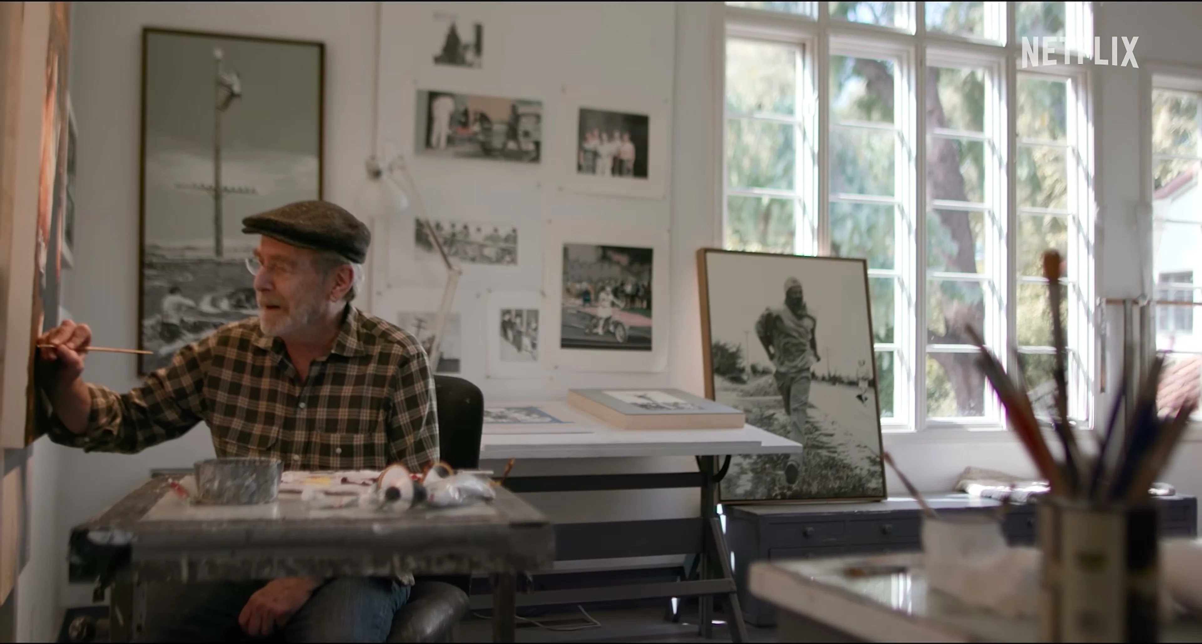 Martin Mull holds a paintbrush at a worktable in his art studio