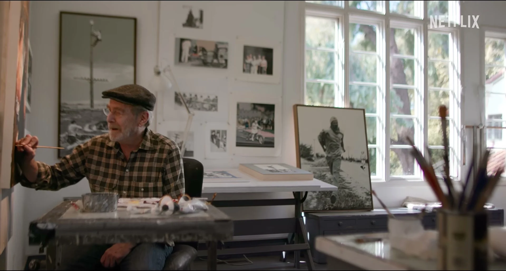Martin Mull holds a paintbrush at a worktable in his art studio