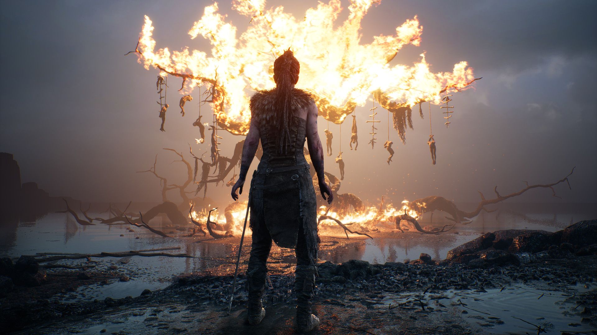 Senua stands before a large burning structure.