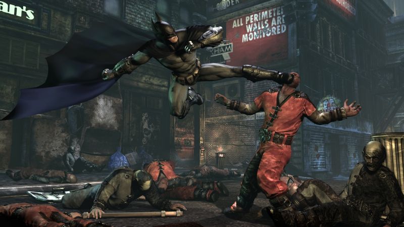 Batman kicks an opponent in a red prison uniform while other attackers gather nearby.