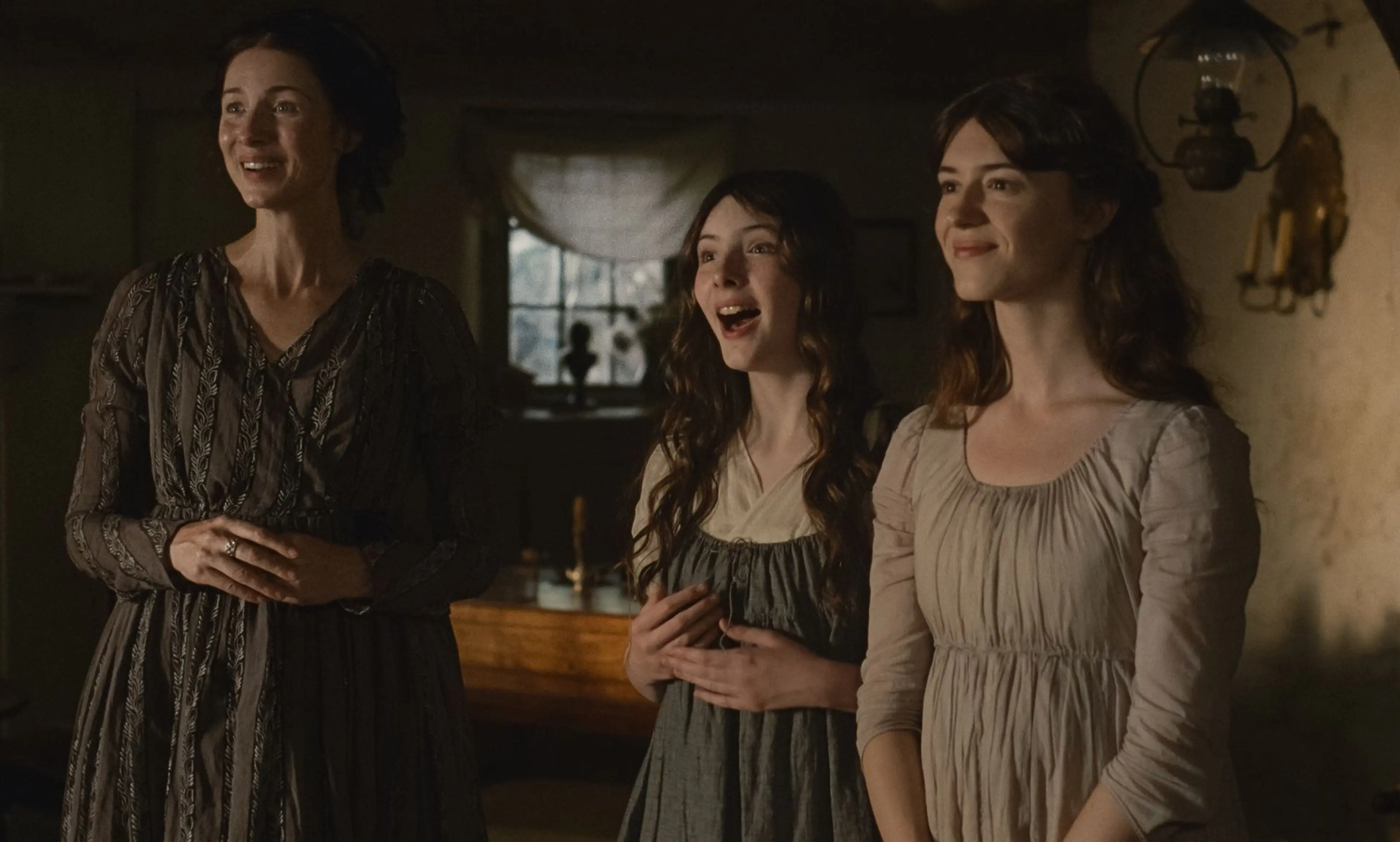 Mrs Dashwood, Margaret and Elinor smile together inside their home.