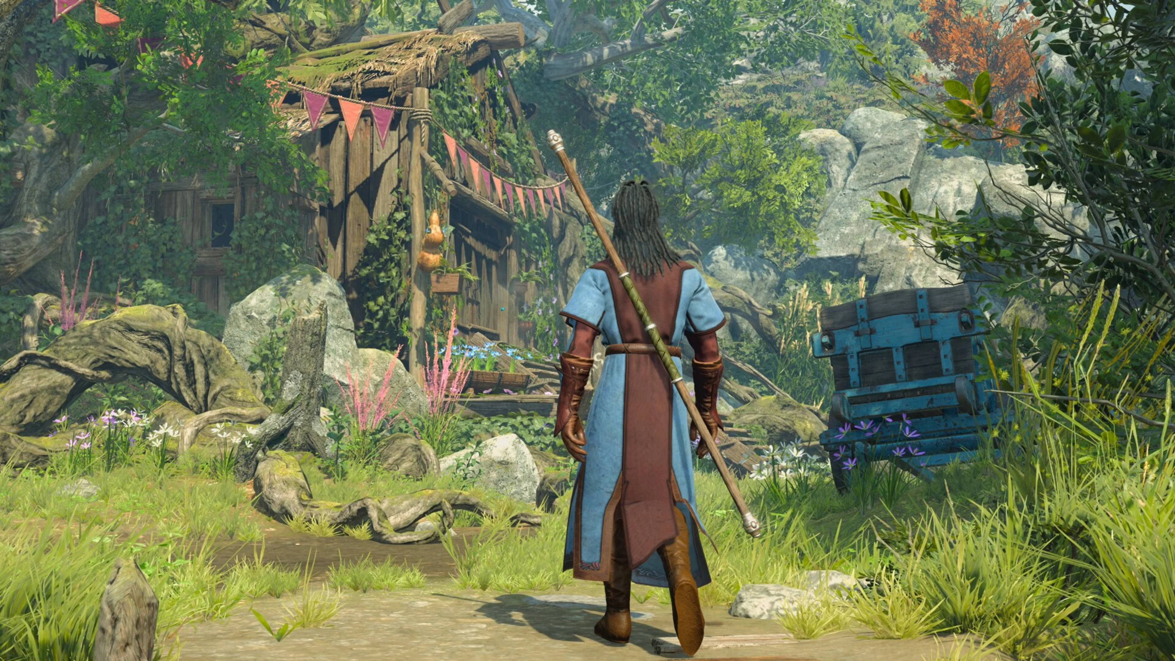 A spellcaster explores a forest settlement beside a locked chest in Baldur's Gate 3.