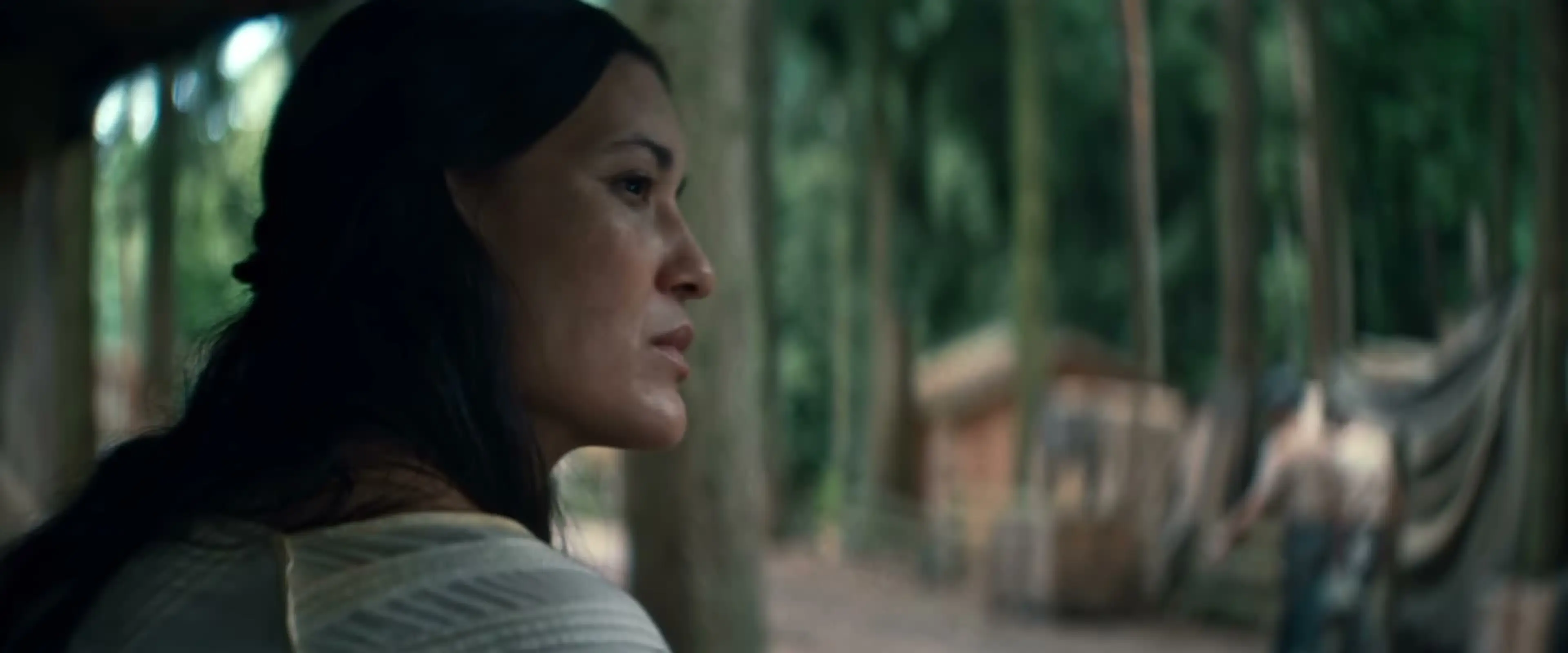 Julia Jones as Anna looks across a forest clearing.