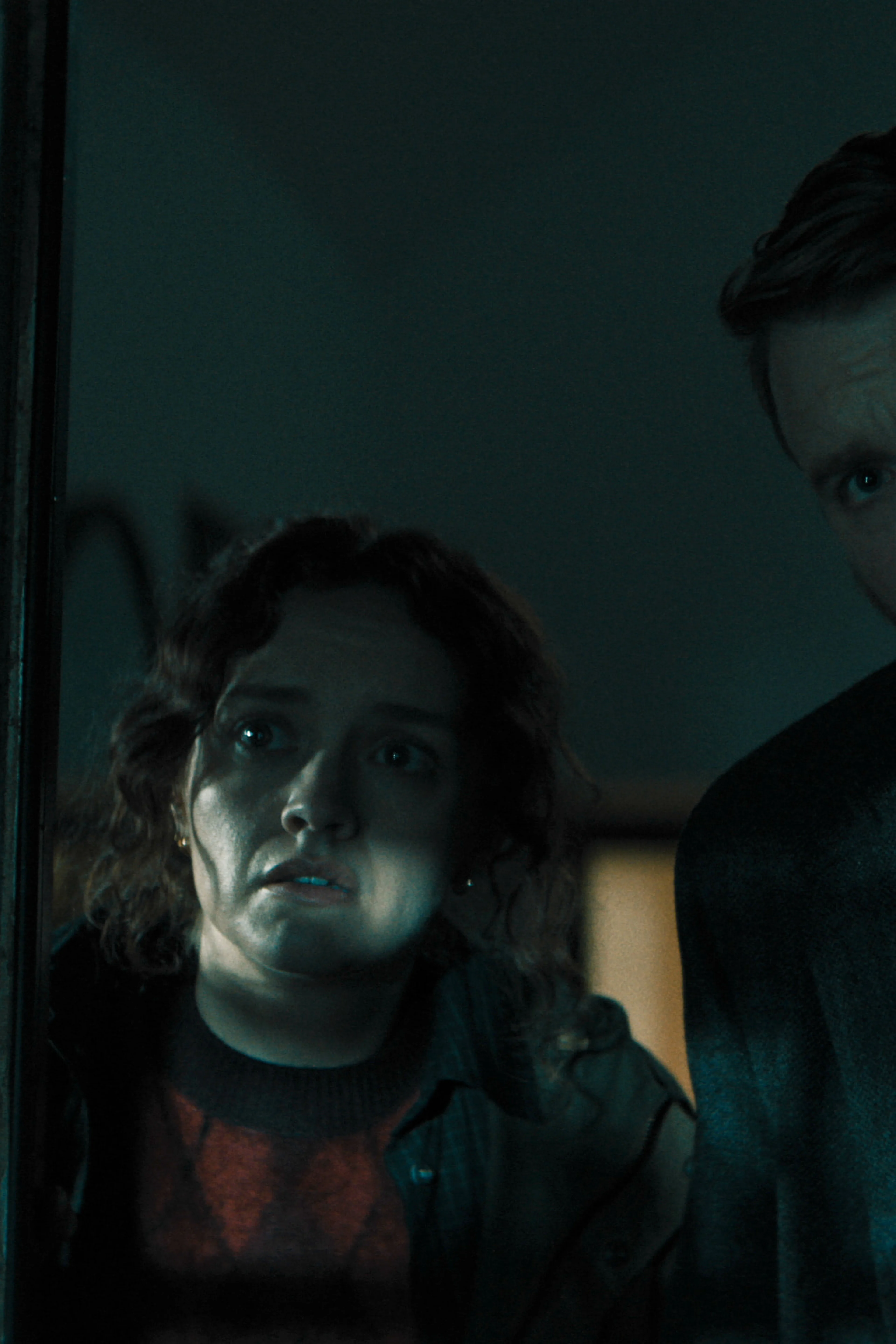 Sid Baker and River Cartwright peer through a doorway together.