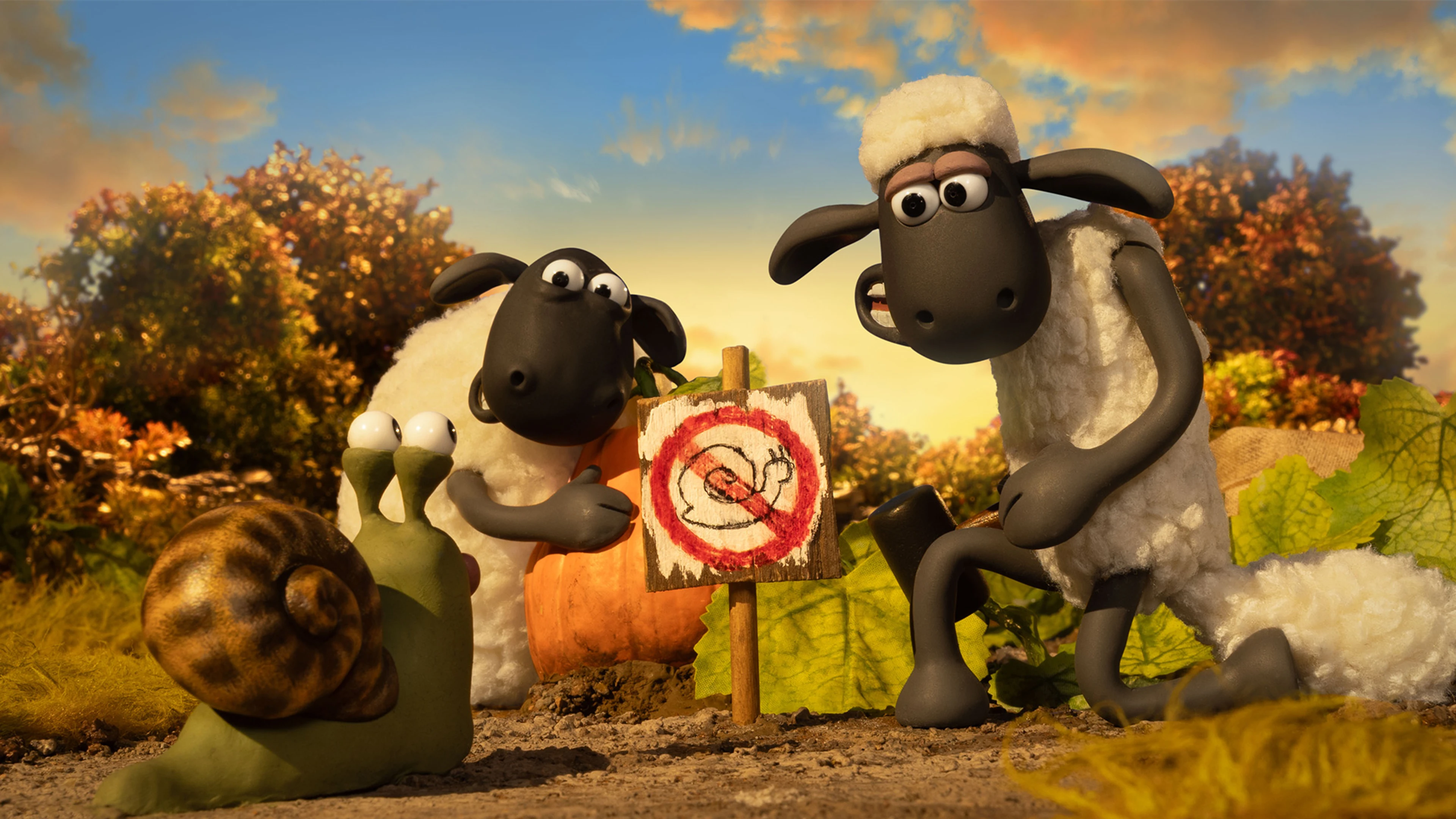 Shaun and another sheep look at a snail beside their Halloween pumpkin patch.