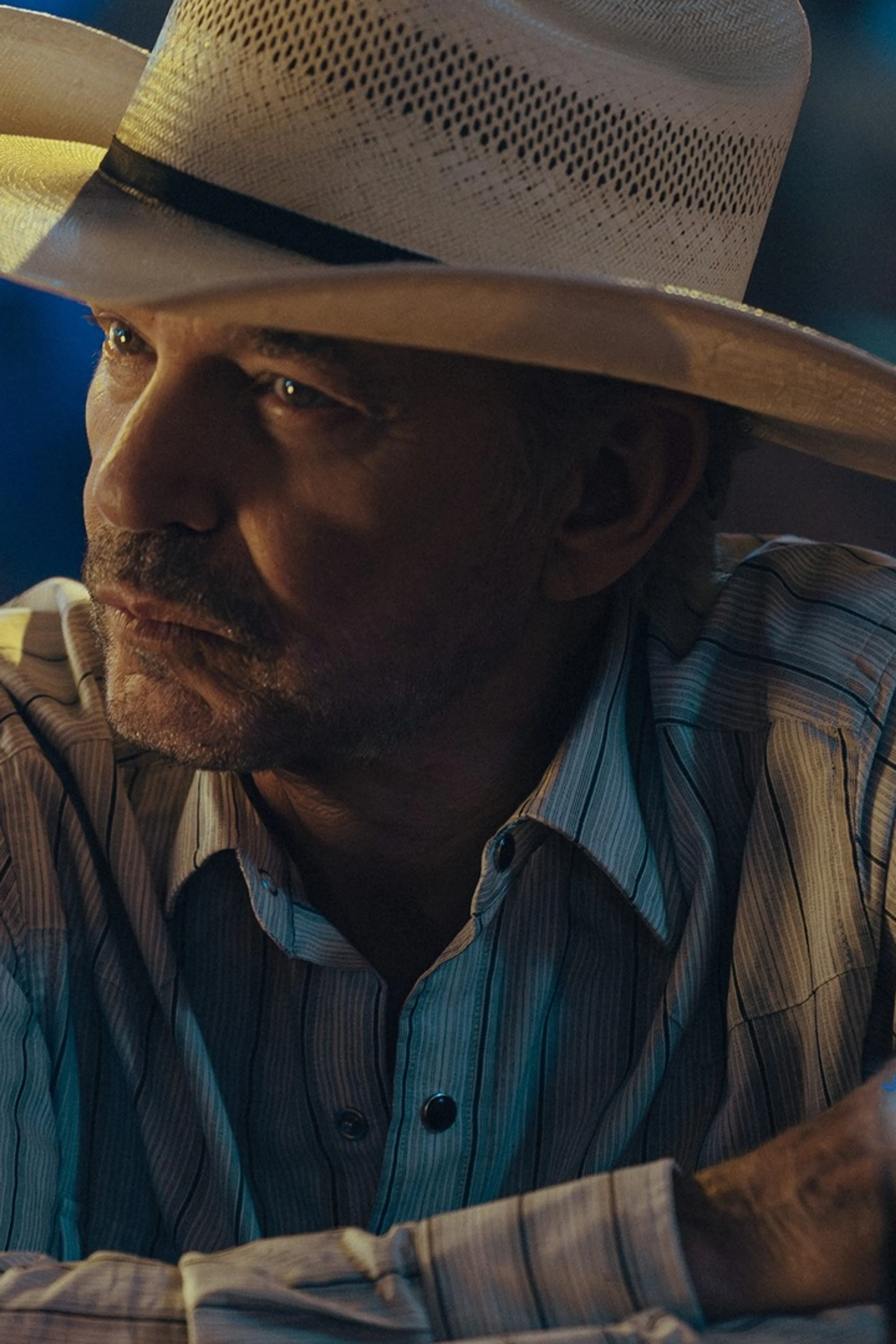 Billy Bob Thornton as Tommy Norris sits at a table at night in Landman.