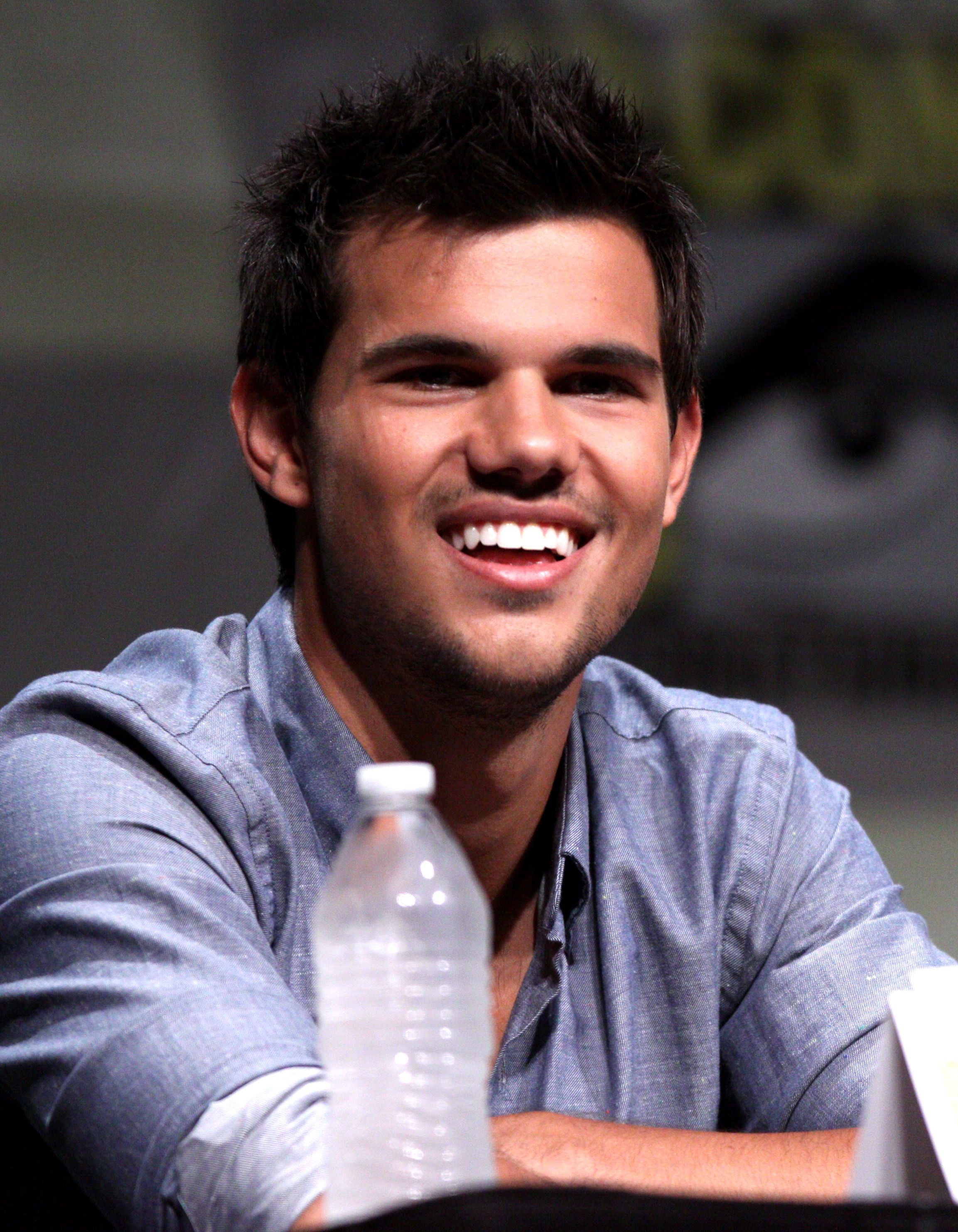 Taylor Lautner smiling at a 2012 Comic-Con panel.