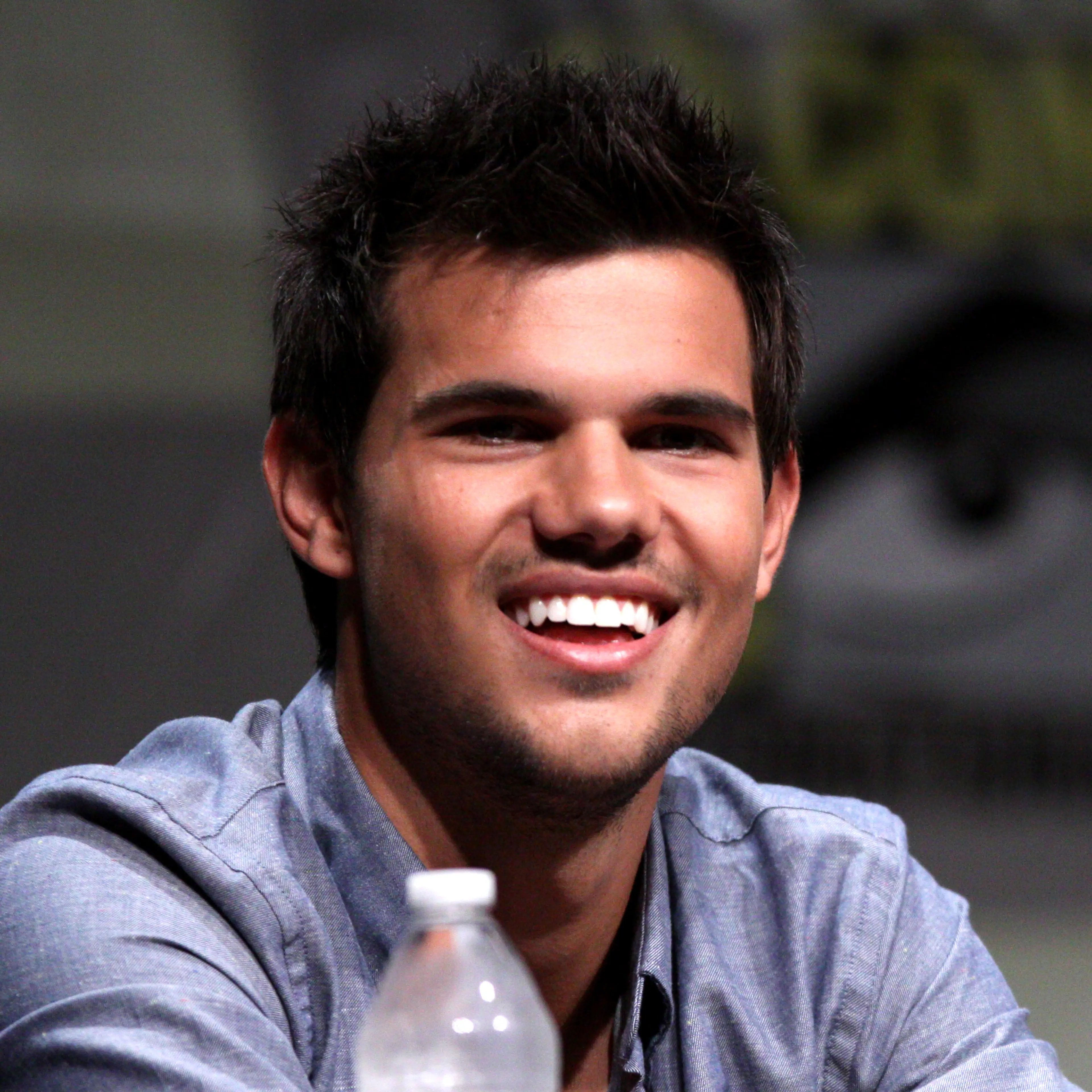 Taylor Lautner smiling at a 2012 Comic-Con panel.