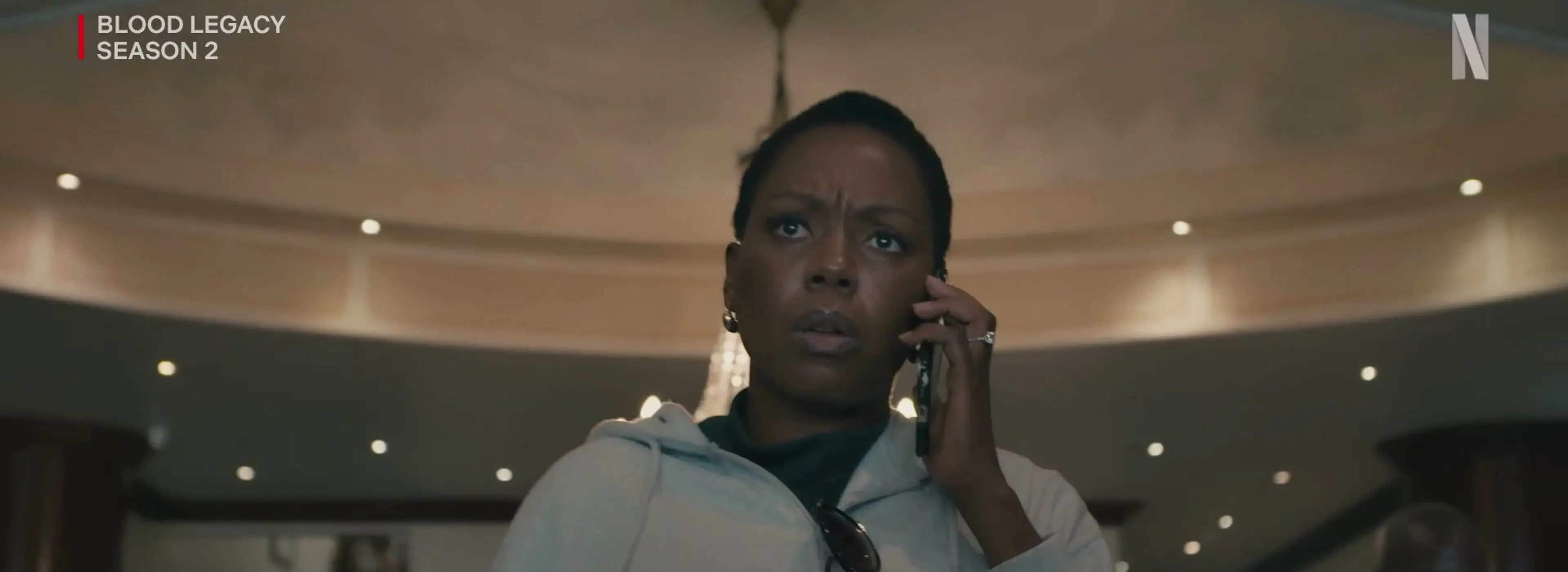 A Blood Legacy character talks on the phone in a grand interior.