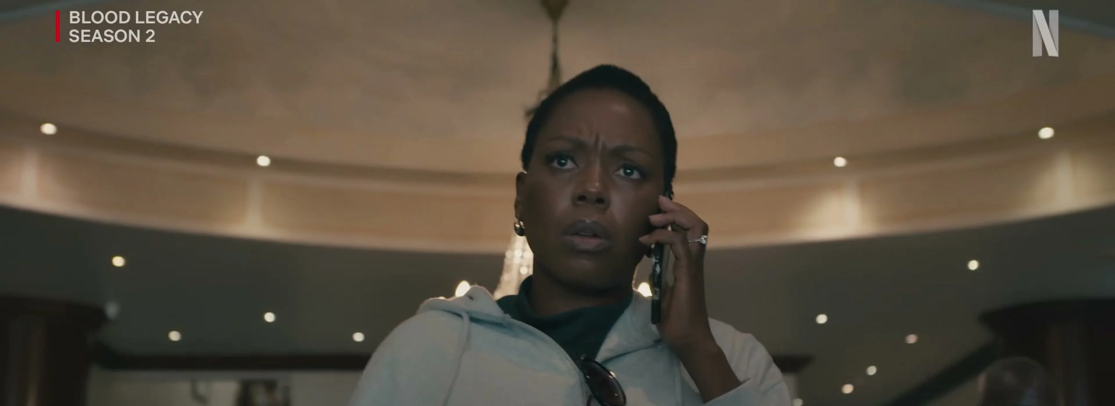 A Blood Legacy character talks on the phone in a grand interior.